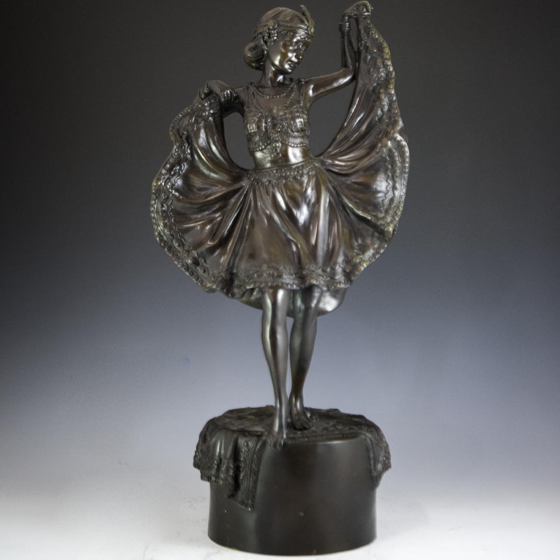 In the Manner of Franz Bergman (Austrian 1861-1936): DESCRIPTION: A Vienna bronze sculpture in the manner of Franz Bergman of a Jugendstil era dancer raising the ends of her dress as she stands atop a cylindrical base adorned with an Oriental rug. Finis