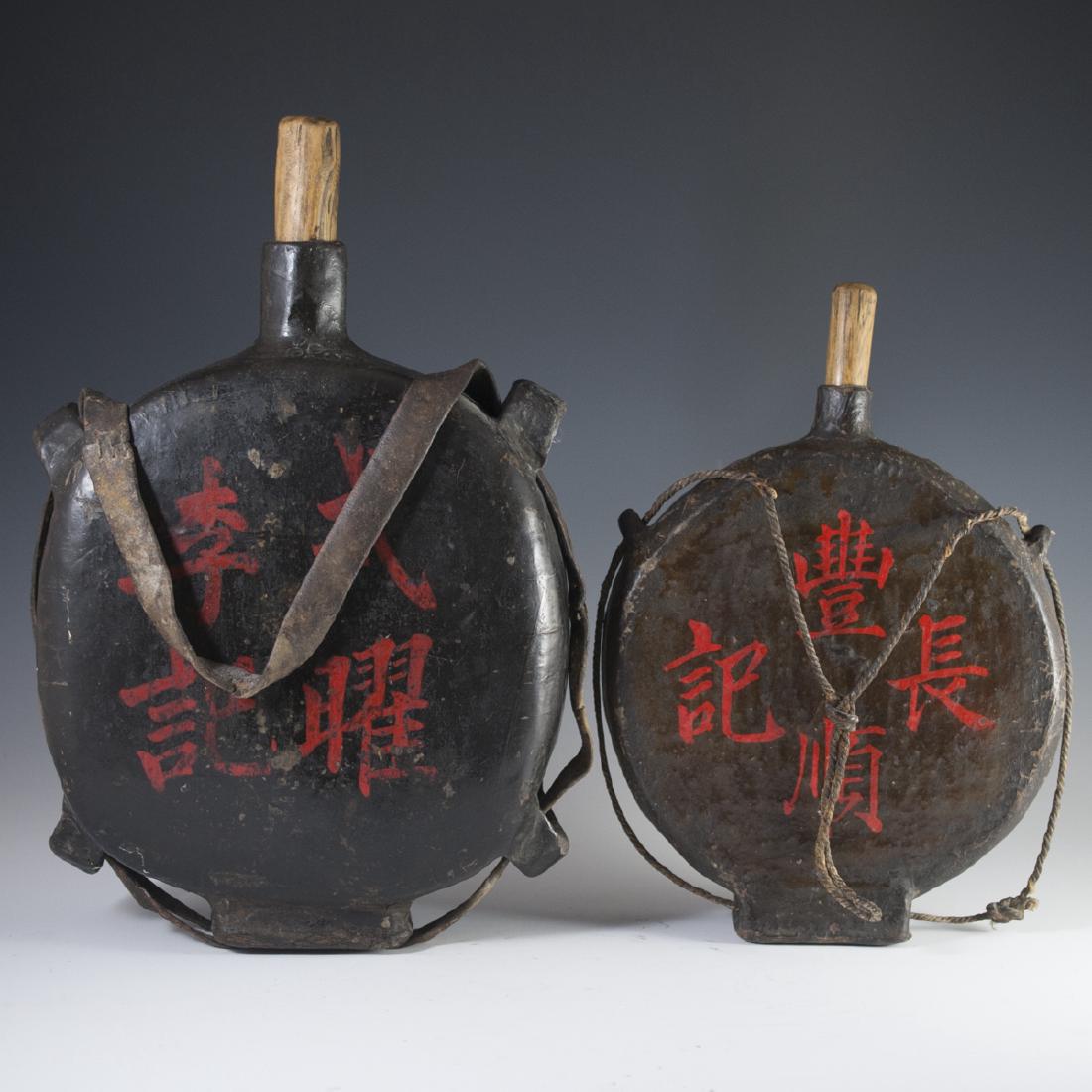 Antique Chinese Wooden Flasks: DESCRIPTION: Antique Chinese wooden flasks. Features a leather strapped rope for hanging along with simplistic circular design, wooden stopper and red Chinese characters. CIRCA: 19th Ct. ORIGIN: China