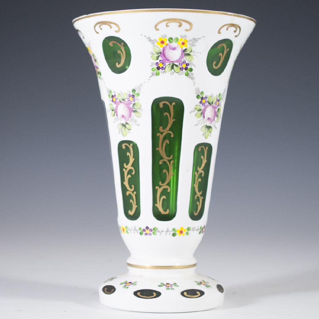 Bohemian Overlay Glass Vase: DESCRIPTION: Bohemian overlay glass vase. Features an emerald green hue with white overlay, handpainted with floral motif and gilded rococo accents. Oval and circular cuts reveal the green glass inter