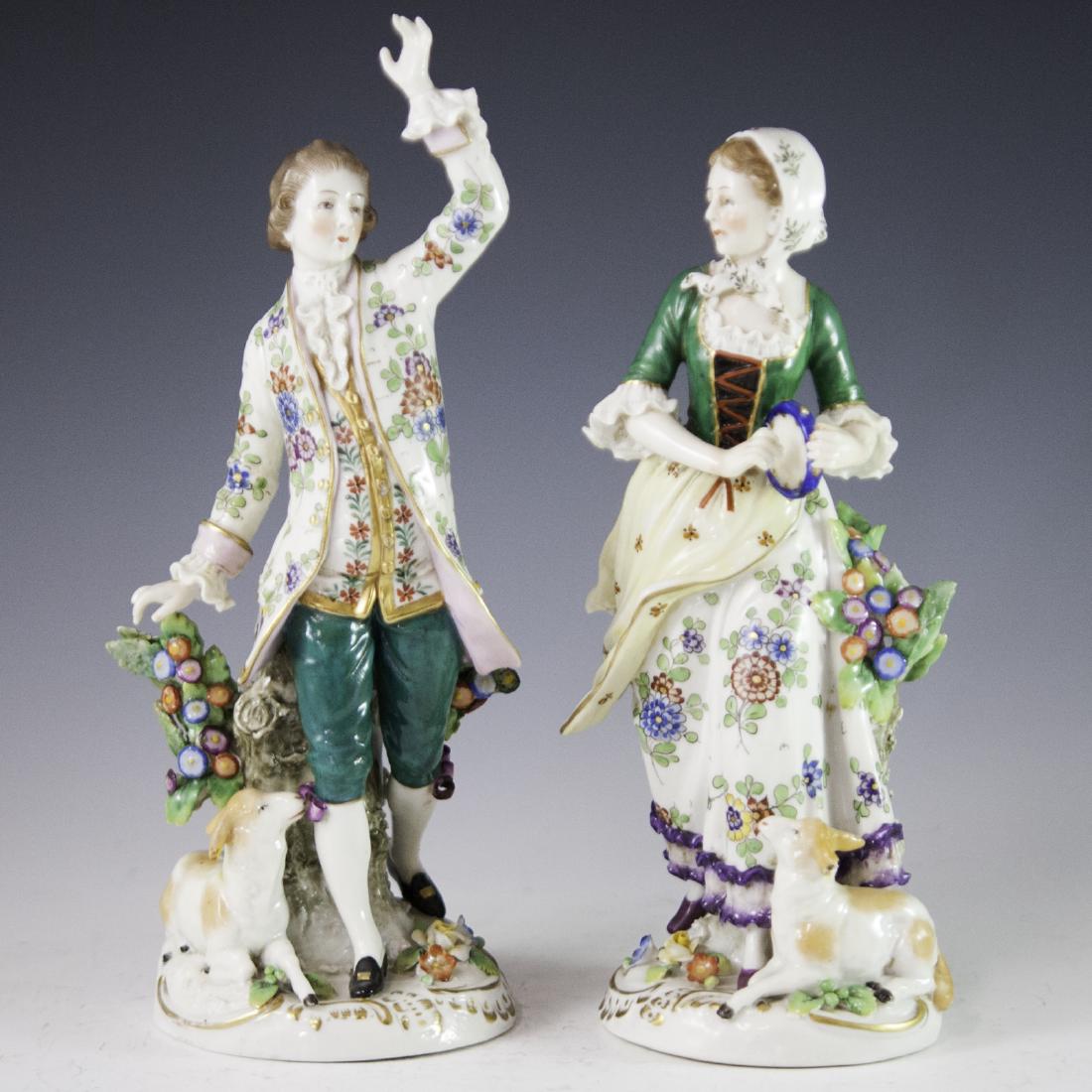 Chelsea Style Porcelain Figurines: DESCRIPTION: A pair of Chelsea style porcelain figurines. Features an edwardian era couple, with the man raising his left arm upwards while leaning against a tree stump with a small sheep by his side.