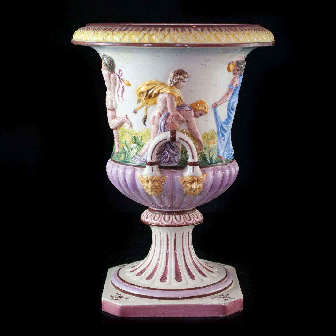 Capodimonte Vase: DESCRIPTION:Capodimonte porcelain vase features a greco-roman style body with a column base wide rim and figural handles. The vase is decorated with raised nude and lady figures hand painted in pink,