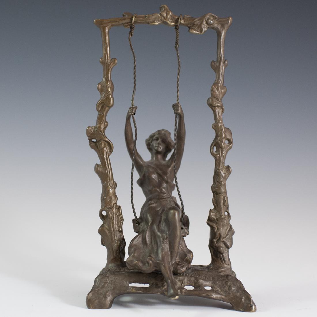 After Auguste Moreau (French 1834-1917): DESCRIPTION: A bronze sculpture after Auguste Moreau. Features a maiden swinging from a swingset lined by creeping vines and floral accents. Swing is fitted with metal wires, allowing it to move. Fini