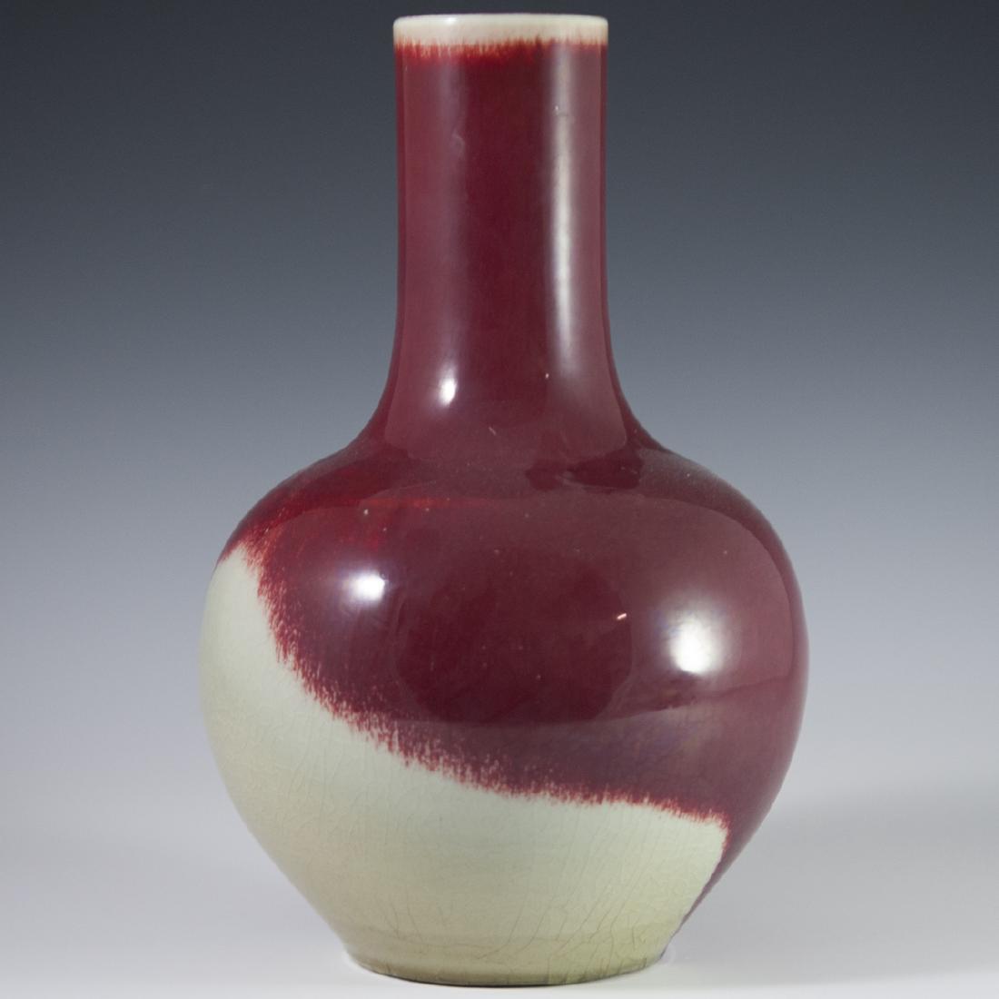 Chinese Flambe Sang De Boeuf Bottle Vase: DESCRIPTION: A Chinese flambe sang de boeuf vase. Features bottle form with a bulbous body and slimmed cylindrical neck. Embellished with an oxblood hued glaze swirled with beige tints along the botto