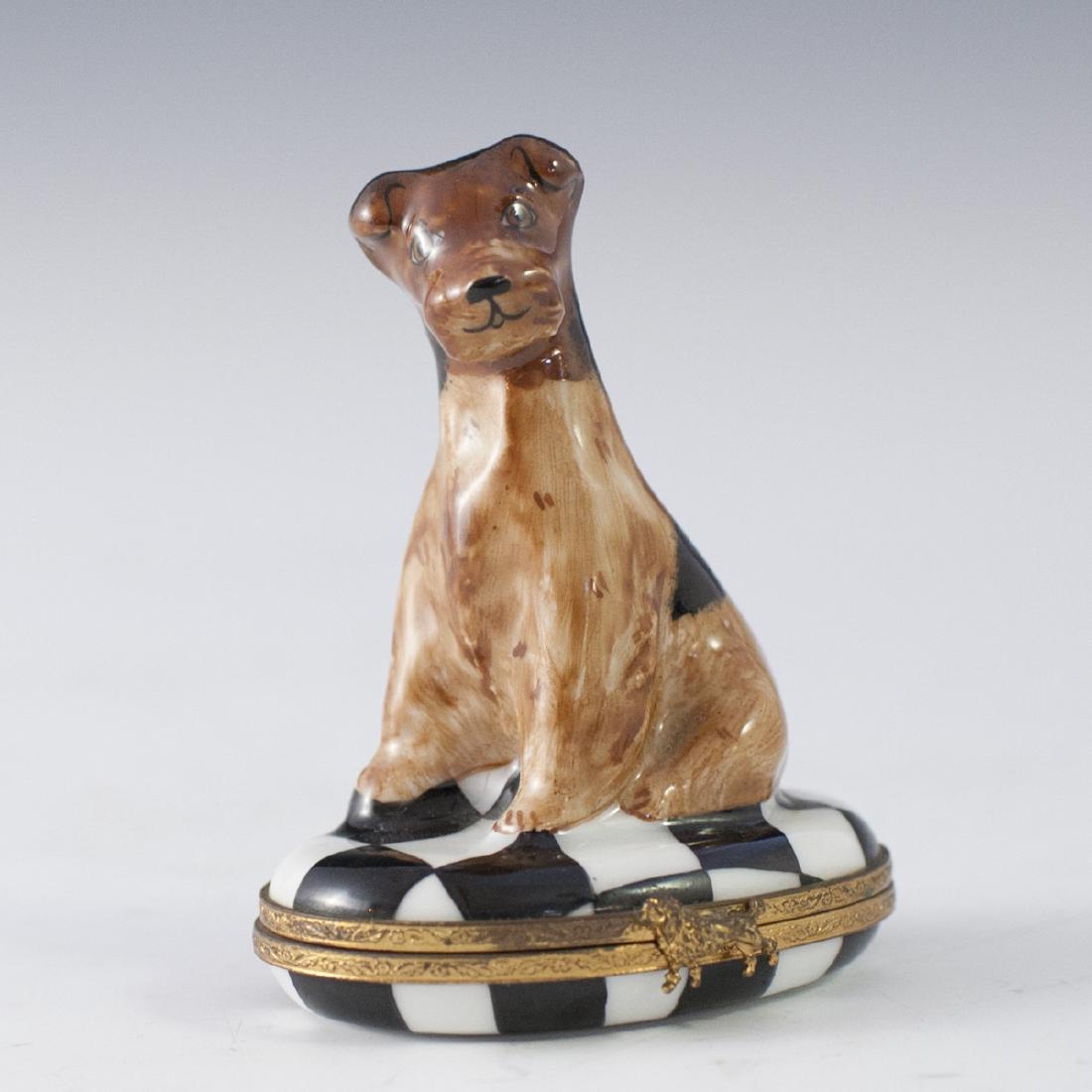 Limoges Porcelain Pill Box: DESCRIPTION: A Limoges porcelain pill box. Features a dog figurine atop a black and white checker designed lid. Finished with a gilt metal lining and a dog motif clasp. Marked along the underside:"Lim