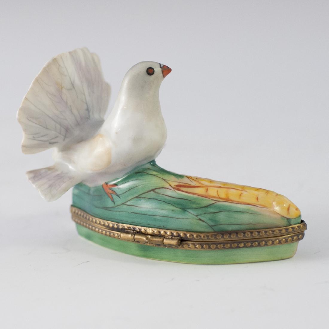 Limoges Porcelain Pill Box: DESCRIPTION: A Limoges porcelain pill box. Features a dove standing atop an ear of corn. Finished with a gilt metal lining and a bird motif clasp. Marked:"Limoges France Peint Main". CIRCA: Mid-Late 2