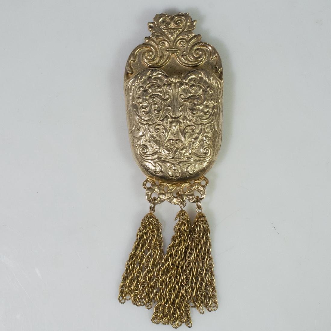 Accessocraft Gilded Brooch: DESCRIPTION: An Accessocraft, gilded brooch. Features a Neo-Victorian design of embossed scrolled rococo foliage and dangling chains along the bottom. Fitted with a slot. Marked:"Accessocraft N.Y.C.".