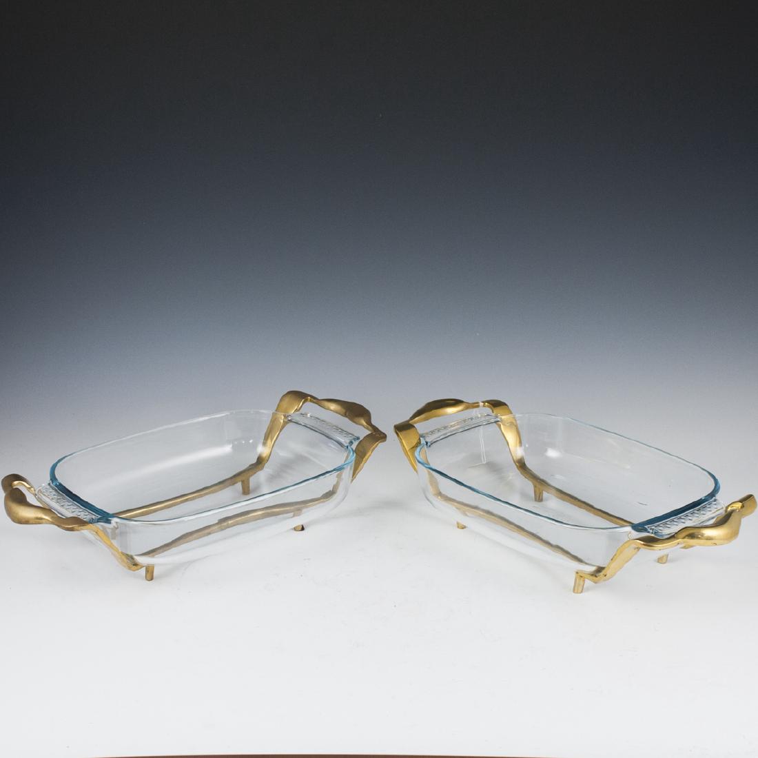 David Marshall Brass Serving Bowls: DESCRIPTION: A pair of David Marshall serving bowls. Composed of brass foundations with sleighed designs and arching handles. Finished with Pyrex glass inserts. Marked with David Marshall marks. CIRCA