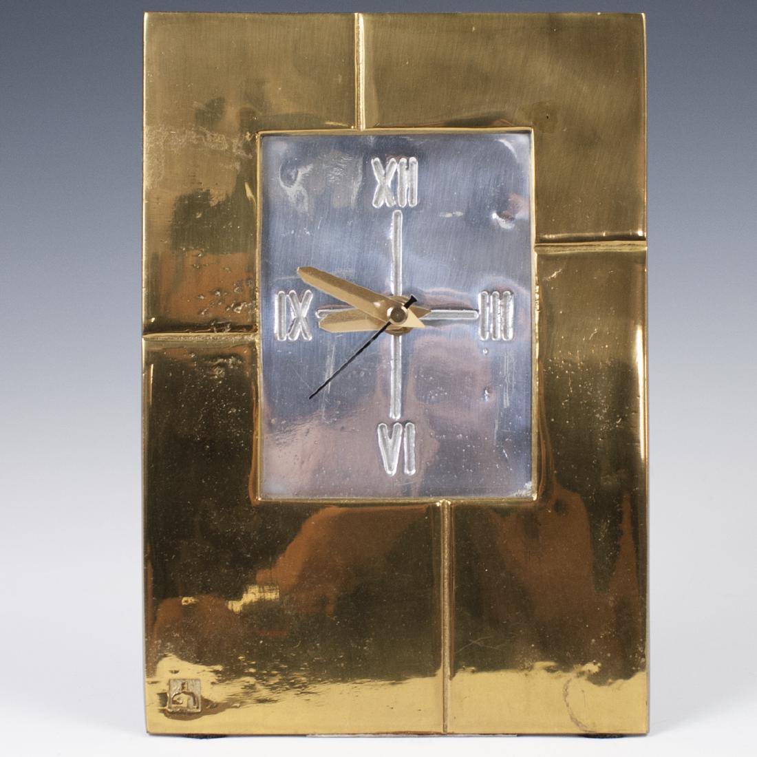 David Marshall "Andes" Clock: DESCRIPTION: A David Marshall "Andes" clock. Features an overall brass foundation with an aluminum face with impressed Roman Numeral dials. Marked with David Marshall stamp. Uses a battery operated mo