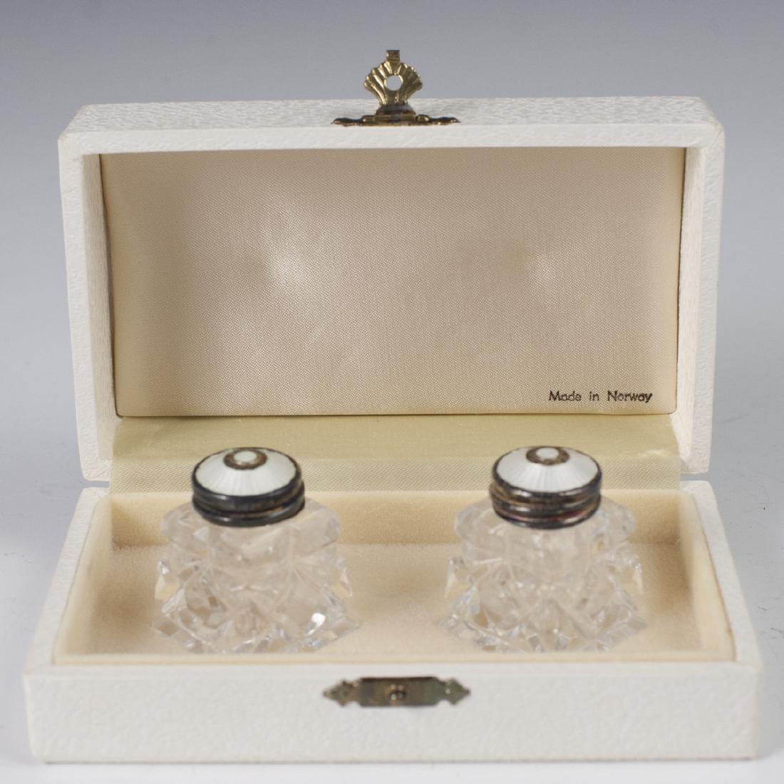 Norwegian Enameled Sterling Crystal Cellars: DESCRIPTION: A pair of salt and pepper shakers, featuring cut crystal bodies, fitted with sterling lids, garnished by a white enamel detailing. Stamped::"Norway 925S Sterling". Includes original box. 