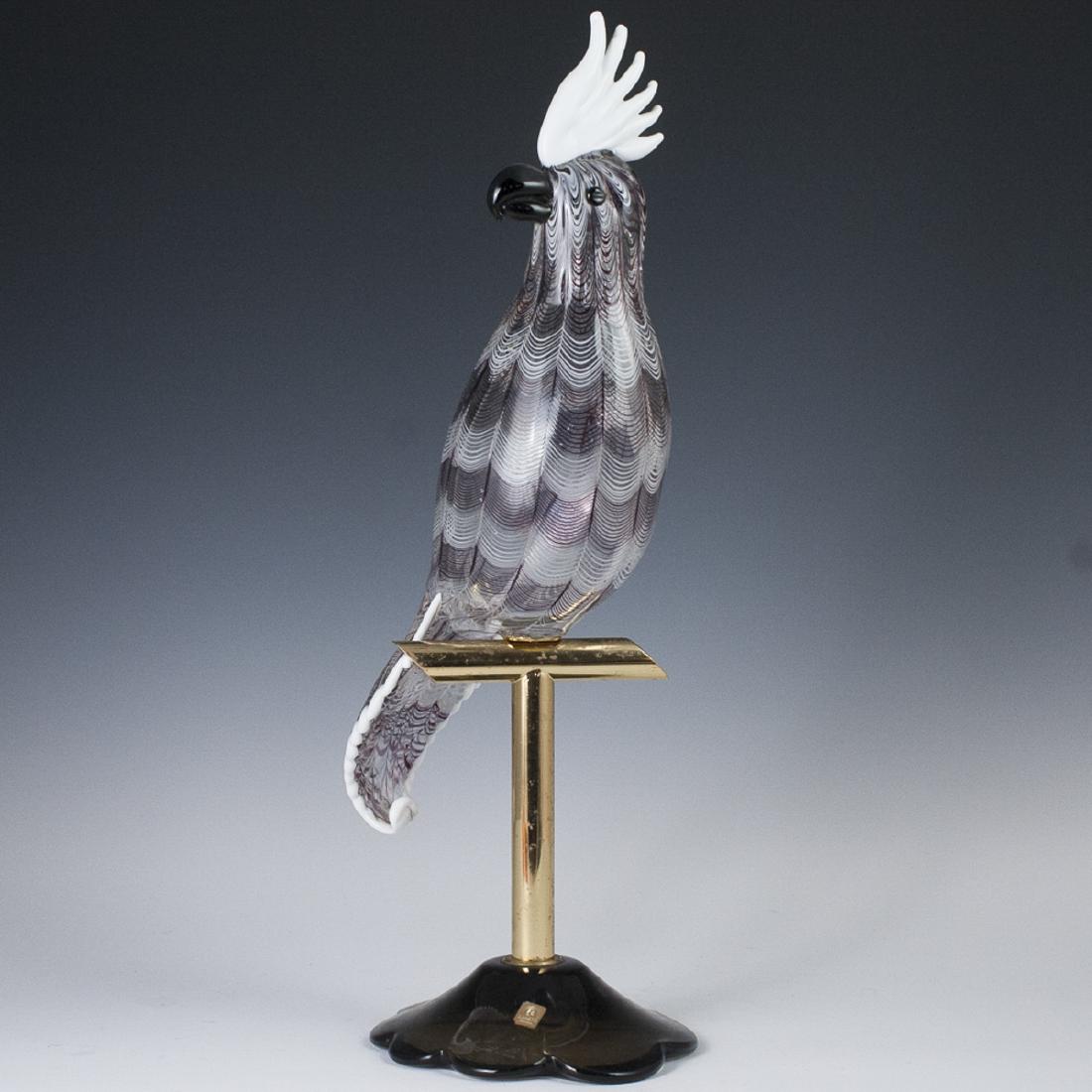Licio Zanetti Murano Glass Cockatoo: DESCRIPTION: A Licio Zanetti Murano glass cockatoo. Composed of a smoky glass, waved base, centered by a brass prong. supporting the glass cockatoo figurine, garnished with feathered accents in white 