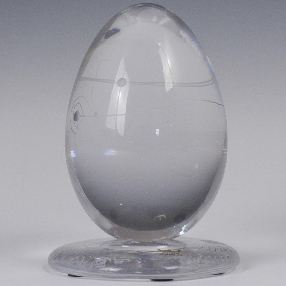 Kosta Boda Goran Warff Crystal Egg: DESCRIPTION: A Kosta Boda Goran Warff designed, crystal egg sculpture. Features a rotund base, centered by an upright egg, garnished striations and abstract designs. Stickered:"Kosta Sweden" and "Kost
