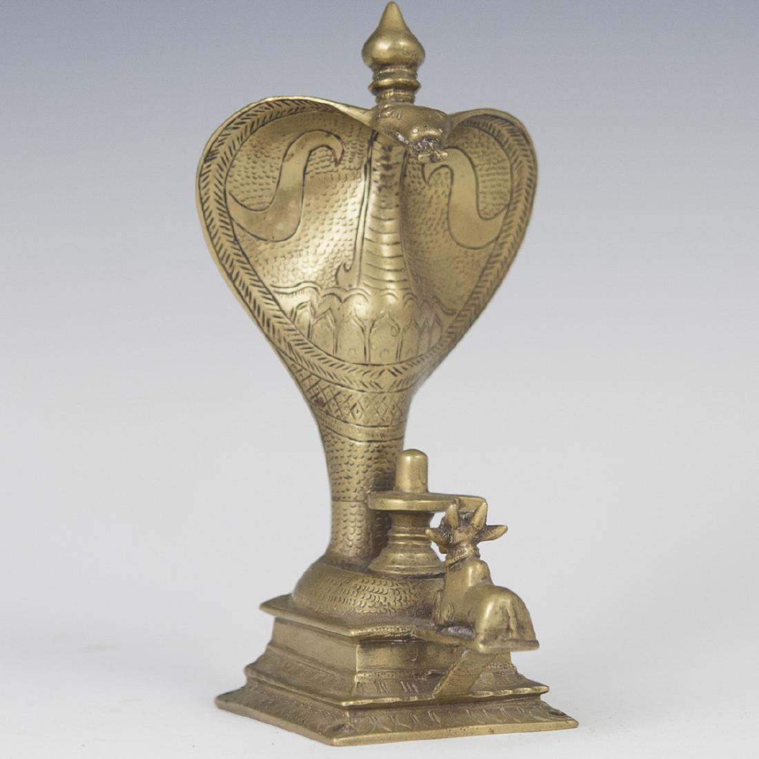 Mughal Bronze Serpent Sculpture: DESCRIPTION: A Mughal bronze sculpture of a cobra topped by a spindled finial, looming over a recumbent goat. Finished with engraved detailing. CIRCA: 19th/20th ct DIMENSIONS: H:7 5/8" L:3.75" W:4" CO