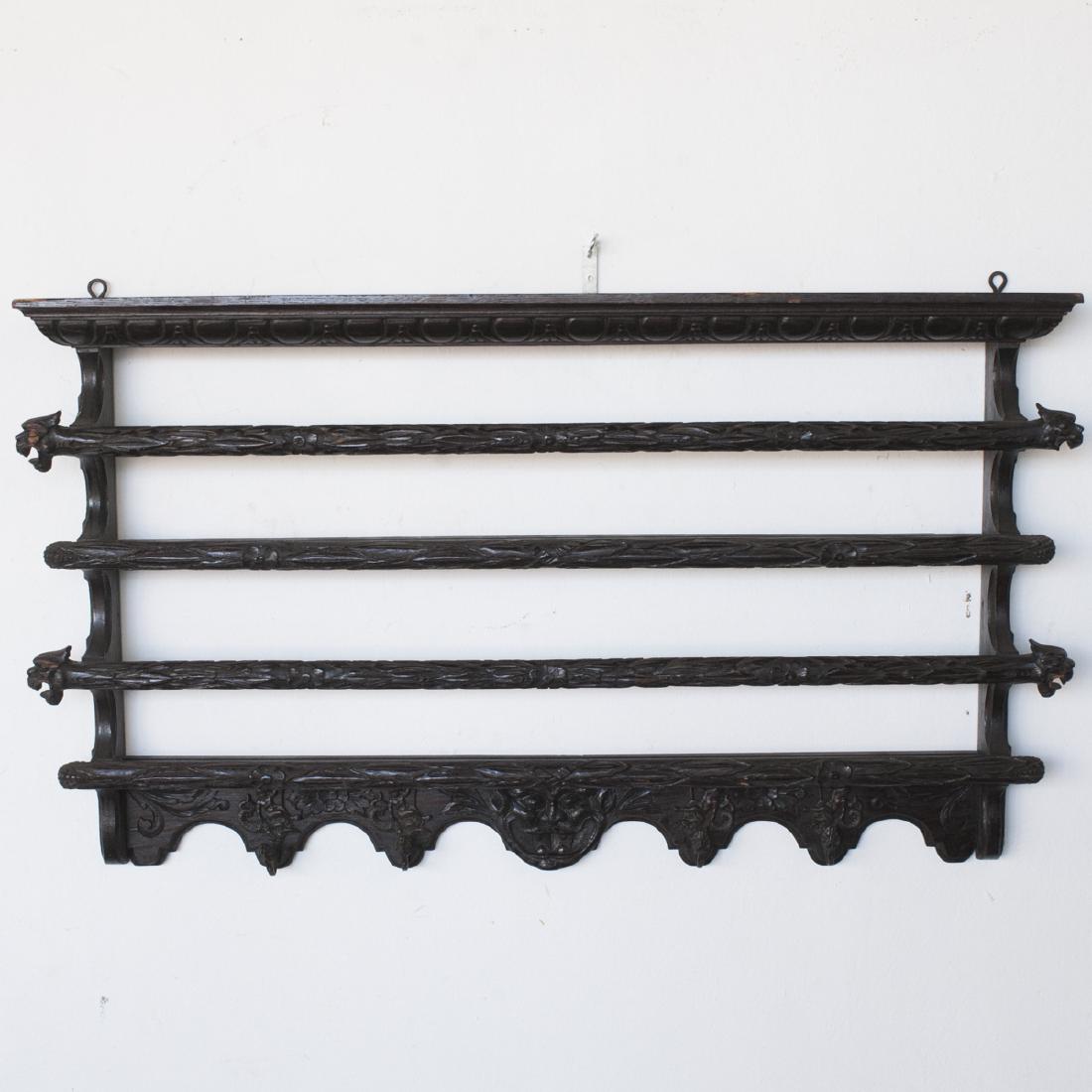 Antique English Carved Wooden Coat Rack: DESCRIPTION: An antique English, carved wooden coat rack. Composed of two shelves with railings carved with overlapping acanthus leaf motifs, and dragon heads along the ends. Along the bottom are 4 br