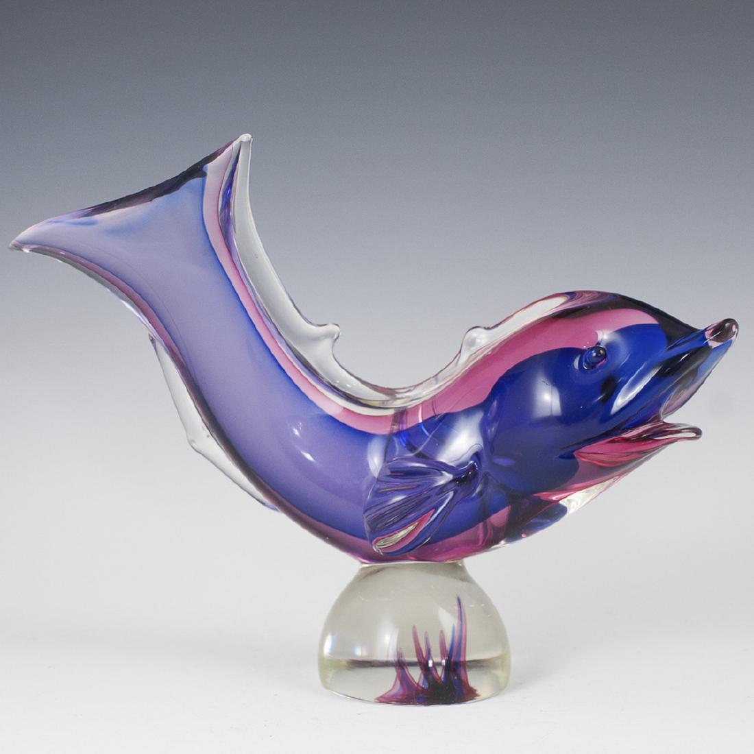Murano Glass Fish Sculpture: DESCRIPTION: A Murano glass sculpture of a fish garnished with a rich interior amethyst and ruby hue. Rests atop a clear glass base with interior amethyst and ruby hued raised striations. Not marked. 