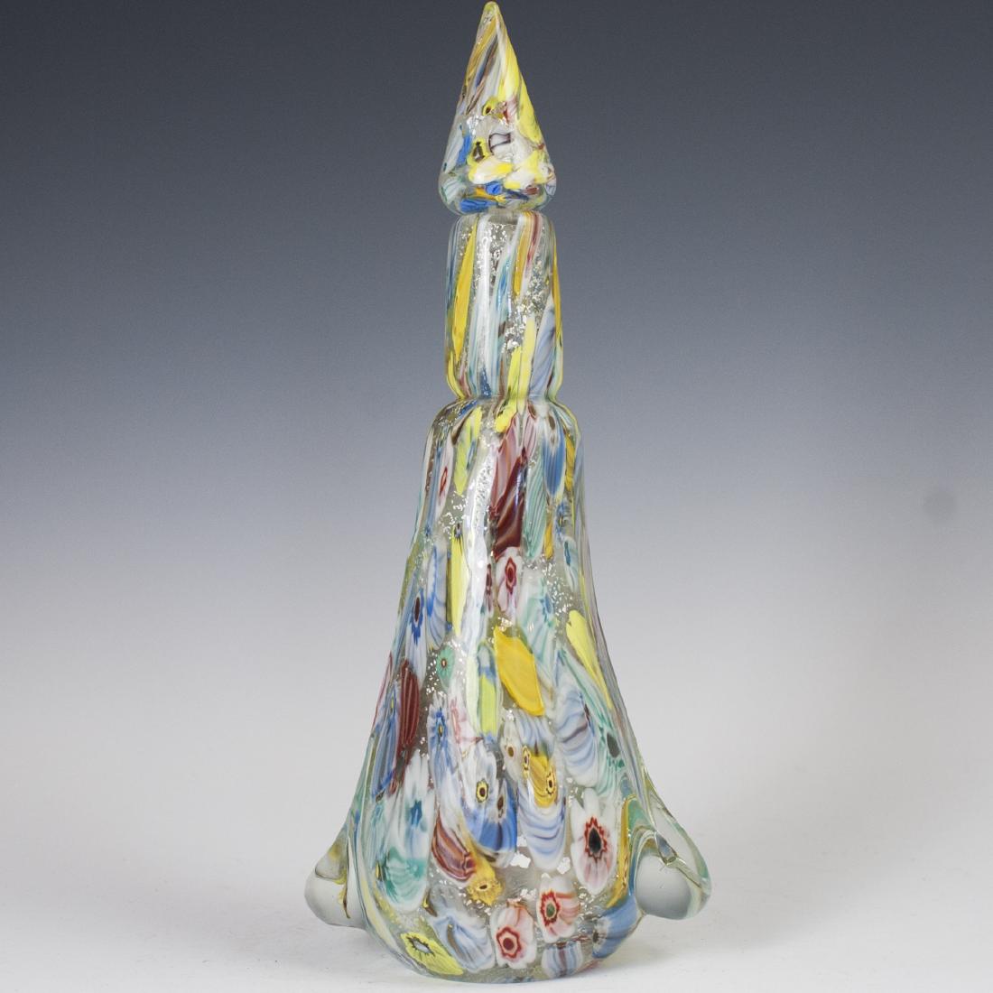 Murano Millefiori Glass Decanter: DESCRIPTION: A Murano glass decanter, embellished with millefiori interior detailing in vibrant, multicolored accents. Finished with abstract concaves flanking the base as well as silver toned glitter