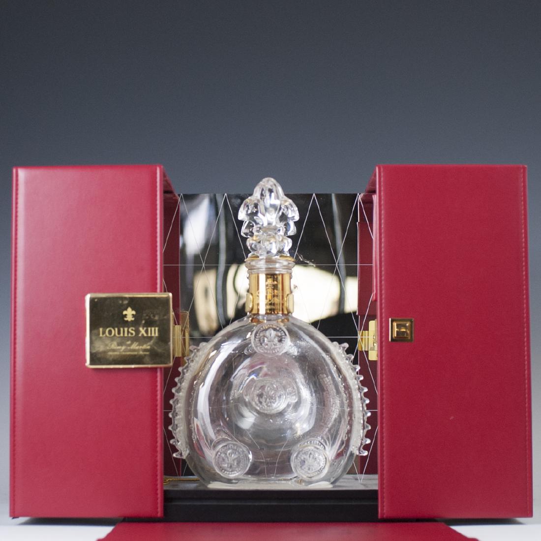 Louis XIII St Louis Crystal Cognac Bottle: DESCRIPTION: A Louis XIII cognac, St. Louis, crystal decanter bottle. Includes original red leather case with sliding panels that reveal the bottle, backed by a mirror panel. Includes a crystal Fleur 