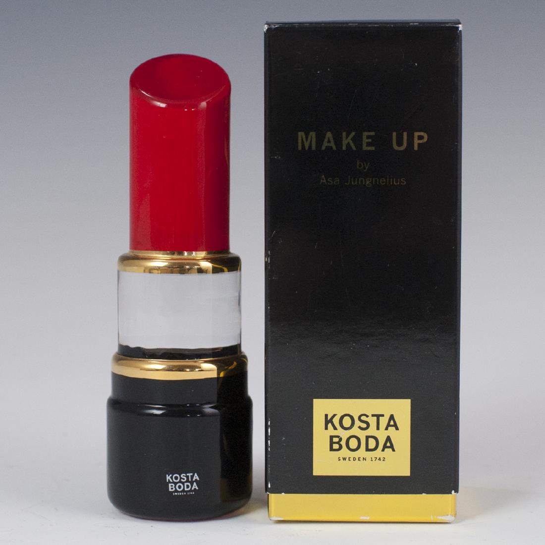 Kosta Boda Asa Jungenelius "Lipstick" Crystal Sculpture: DESCRIPTION: A Kosta Boda sculpture, designed by Asa Jungnelius from the"Make Up" line. Features a lipstick form with hand painted accents along the top and an ebonized base with gilded trims. Sticker