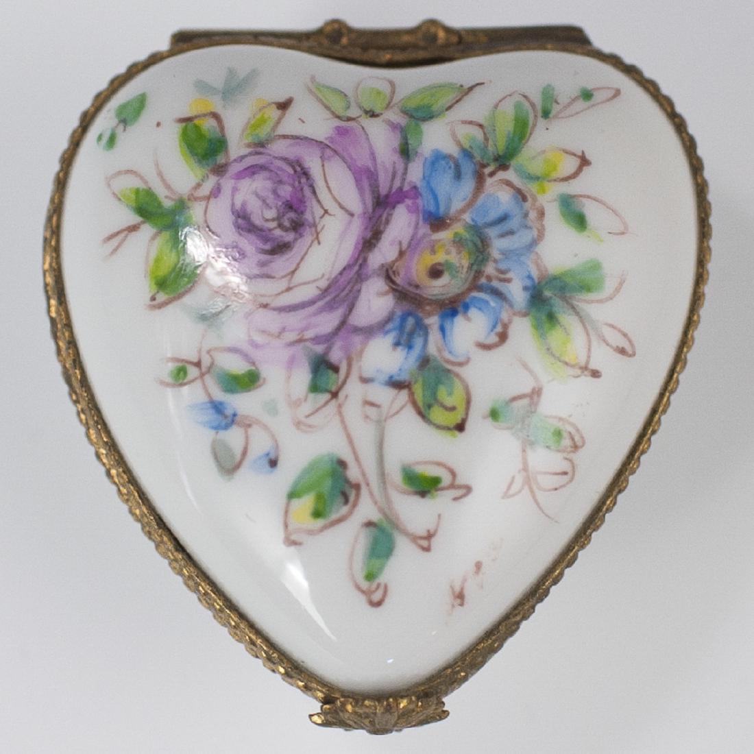 "Paris-Style" Limoges Porcelain Pill Box: DESCRIPTION: A Limoges porcelain pill box. Features a heart shaped form, embellished with floral motifs. Finished with a gilt metal lining and a floral motif clasp. Marked along the underside:" Porcel