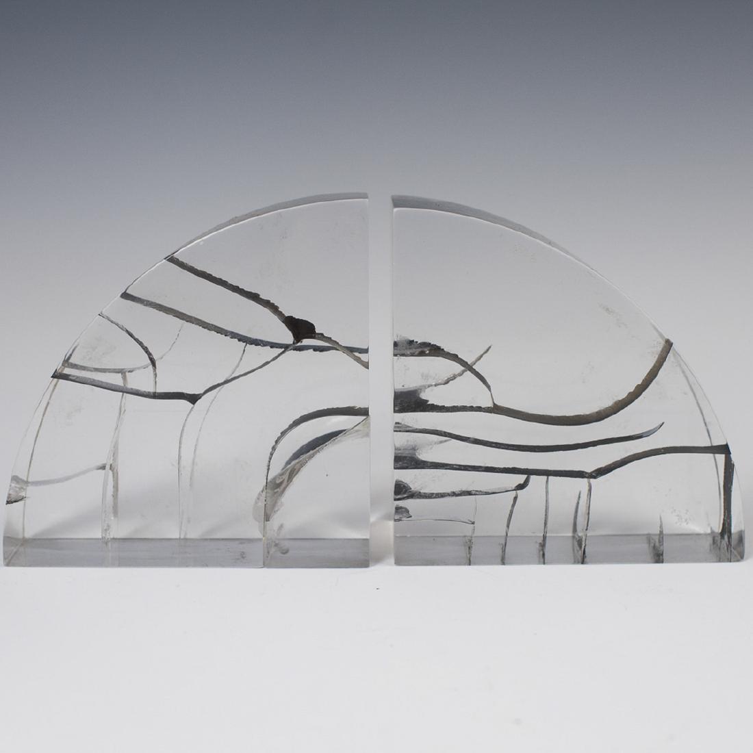 Vintage Herb Ritts Astrolite Acrylic Bookends: DESCRIPTION: A pair of Herb Ritts Astrolite, acrylic bookends, garnished with abstract interior ribbon designs. CIRCA: Late 20th Ct. ORIGIN: USA DIMENSIONS: (Each) H:5.5" L:5.5" W:2.25" CONDITION: Fai
