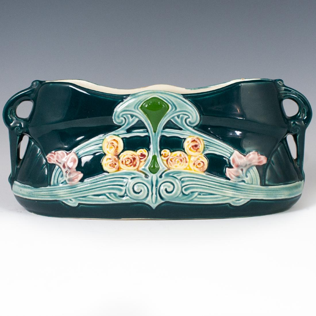 Art Nouveau Majolica JardiniÃ¨re: DESCRIPTION: An Art Nouveau, majolica glazed, ceramic jardiniere. Embellished with embossed, Art Nouveau style, floral motifs and winding detailing. Finished with amphora style handles and an overall