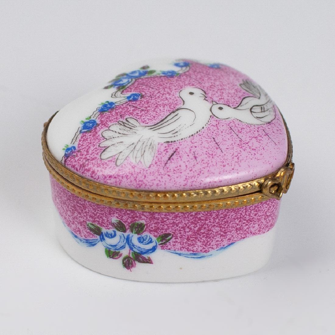 Limoges Porcelain Trinket Box: DESCRIPTION: A Limoges porcelain trinket box. Features a heart shaped foundation ,embellished with doves and floral motifs. Finished with a gilt metal lining and a heart shaped clasp. Marked:"Limoges 