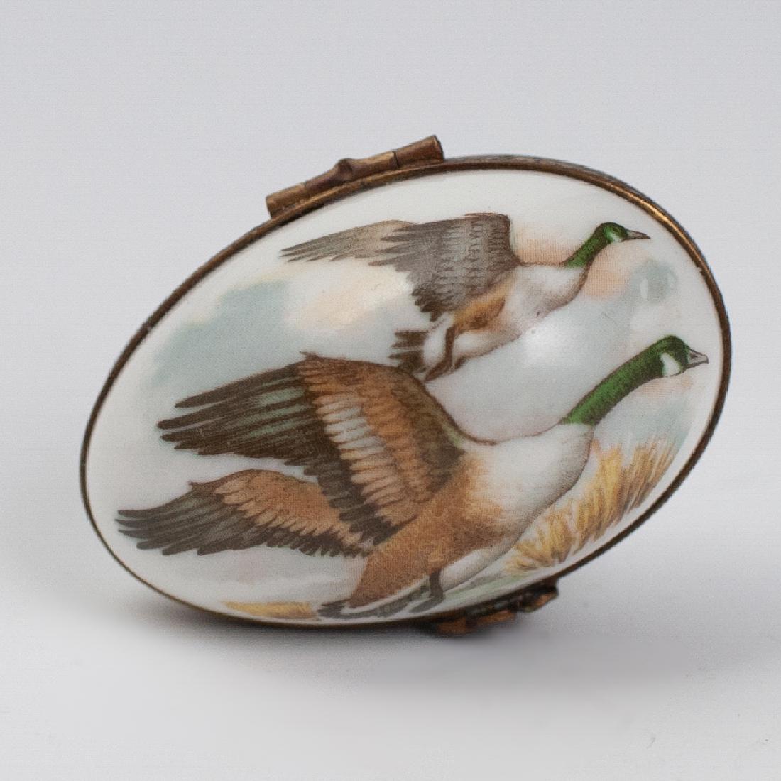 Limoges Porcelain Pill Box: DESCRIPTION: A Limoges porcelain box. Features an ovoid form, embellished with a scene of soaring ducks. Finished with a gilt metal lining and a floral motif clasp. Marked:"Limoges France". CIRCA: Mid