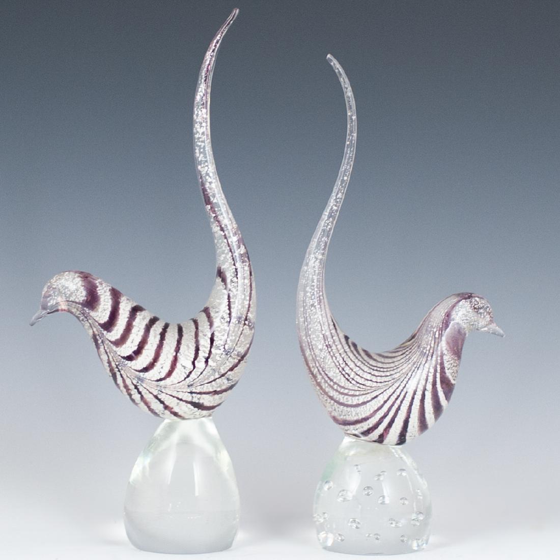 Murano Glass Birds: DESCRIPTION: A pair of Murano glass birds. Embellished with amethyst and silver toned striped detailing. One is finished with interior controlled bubbles along the base. CIRCA: Mid-Late 20th Ct. ORIGI