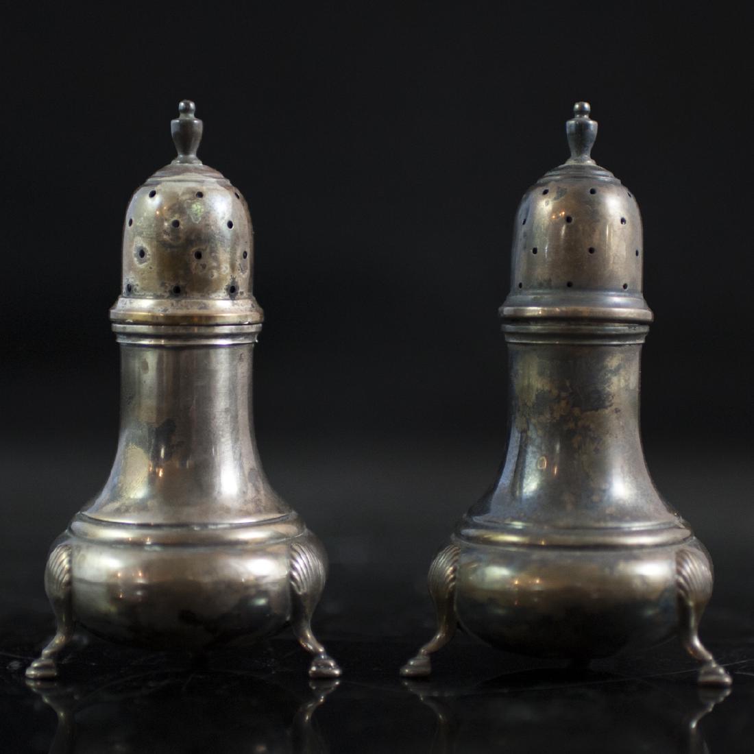 Mueck Carey Co. Sterling Casters: DESCRIPTION: A pair of Mueck Carey Co. Sterling salt and pepper casters. Features rotund bodies with fluted stems and a perforated lid with a finial along the center. Finished with rococo shell motif 