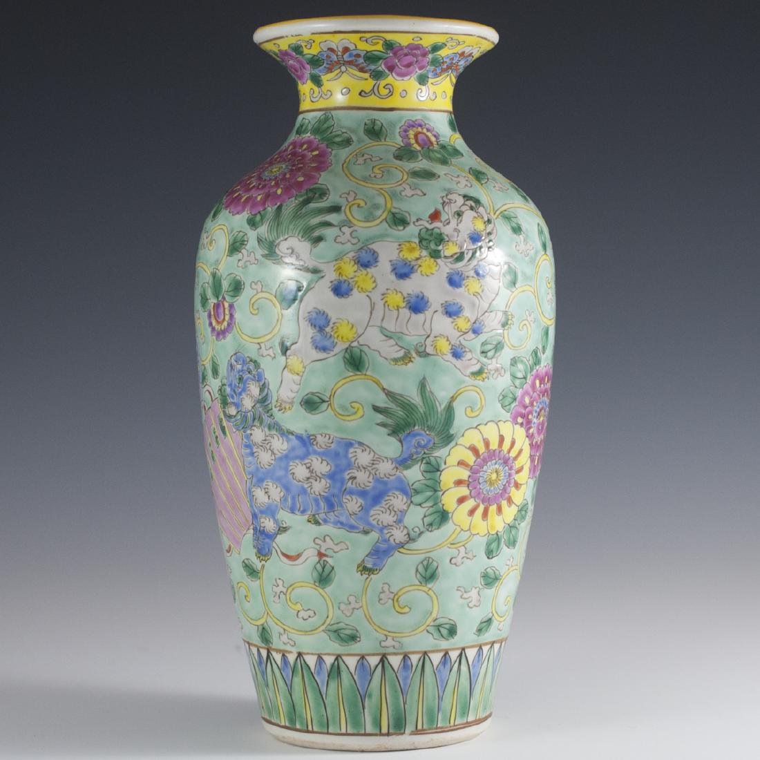 Chinese Famille Rose Porcelain Vase: DESCRIPTION:Chinese Famille Rose porcelain vase. Features handpainted illustrations of foo dogs standing on fans and enveloped in yellow swirled tree branches with stemming leaves. Finished with multi