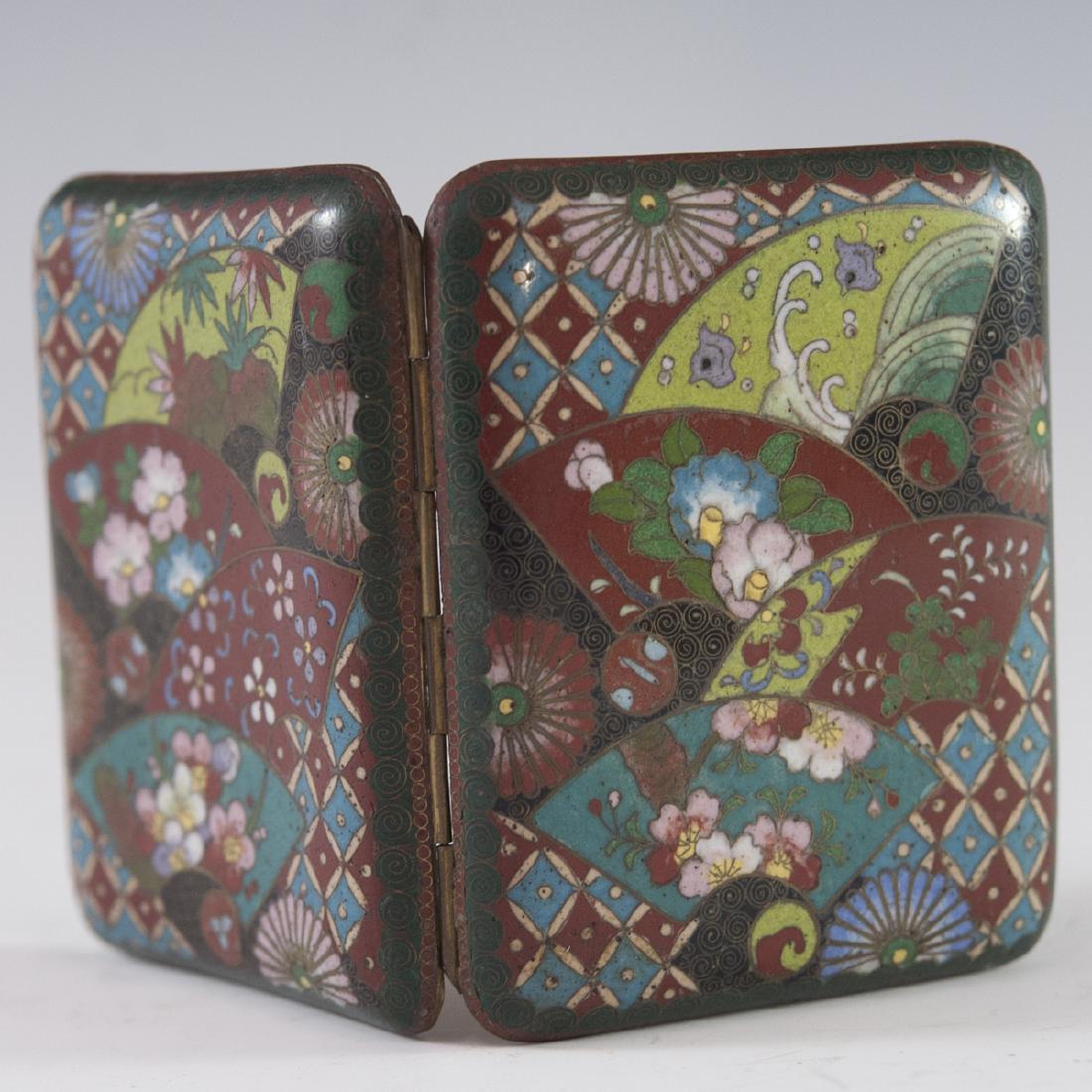 Japanese Cloisonne Enameled Cigarette Case: DESCRIPTION: A Japanese cloisonne enameled cigarette case. Features elegant enameled floral motif along with diamond designs and spiraled accents along the borders. Opens to reveal two elastic straps 