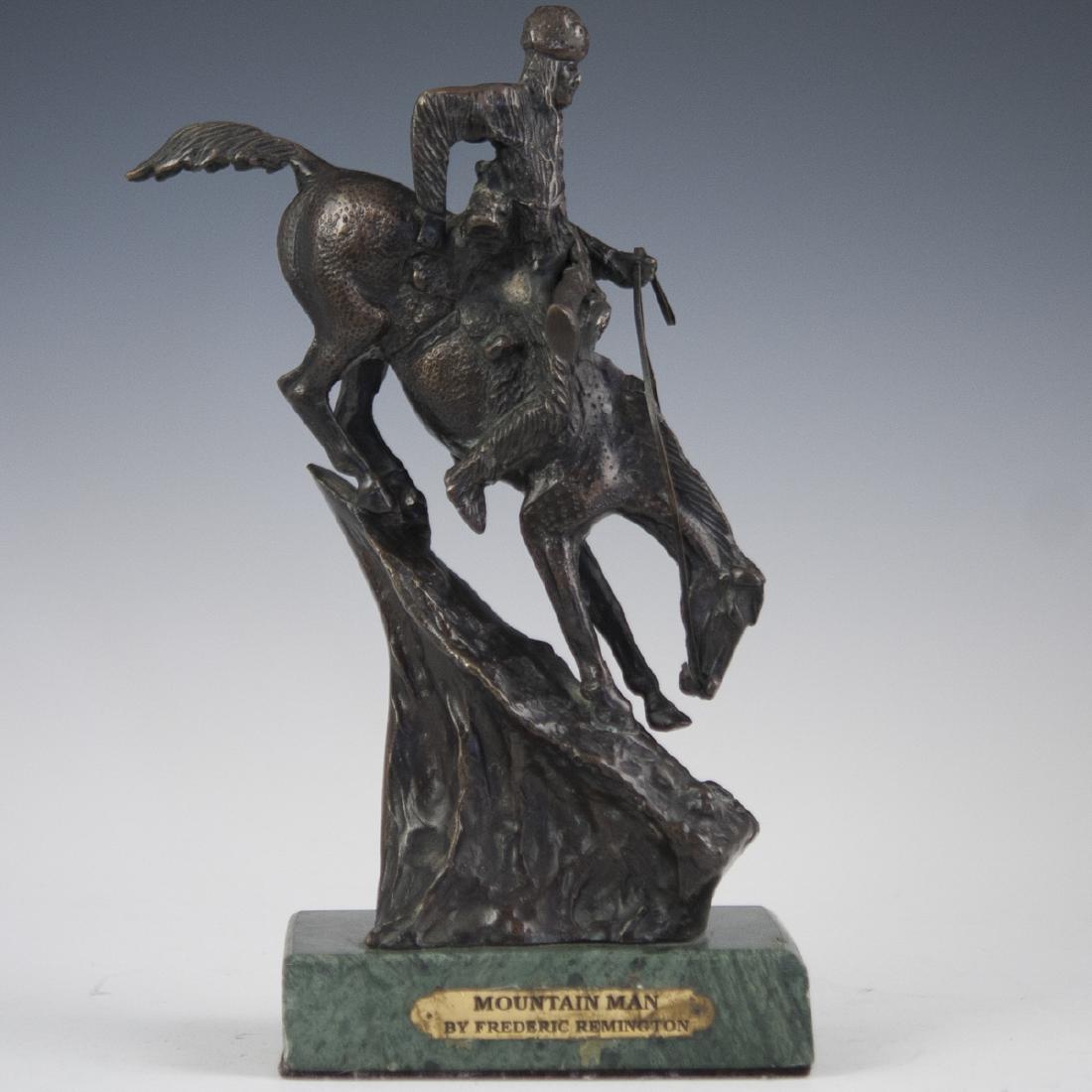 Copy Of Frederic Remington (American 1861-1909): DESCRIPTION: A miniature bronze sculpture of Frederic Remington's "Mountain Man". Features a Native American man with a sheathed rifle on horseback, riding down a steep decline, textured base. Fitted 