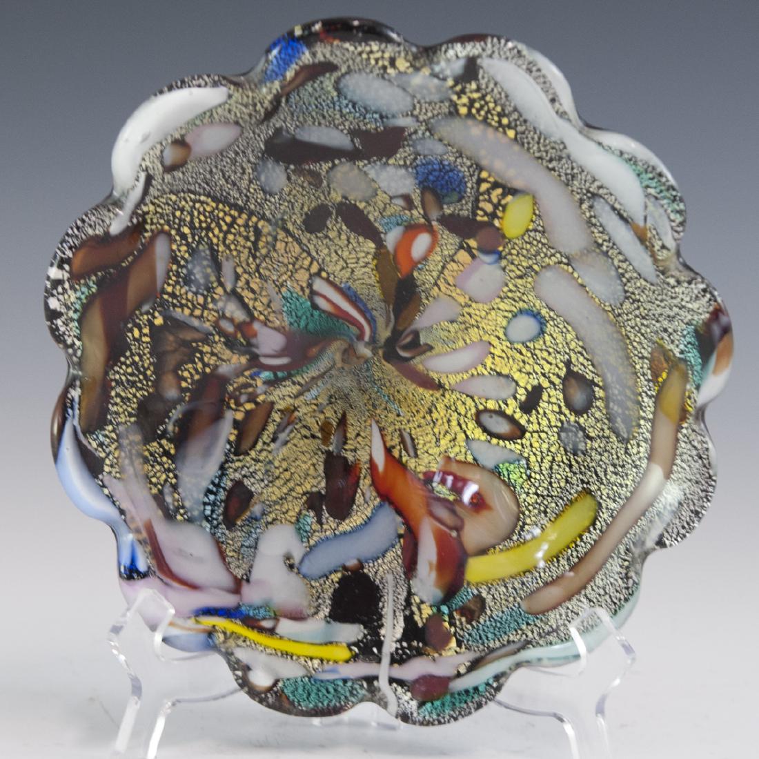 Murano Glass Bowl: DESCRIPTION: A Murano glass bowl. Features a rotund form with waved, ridged, edgework enveloping the scalloped center. Features an overall ebonized base hue garnished with multi-hued swirls and gilded