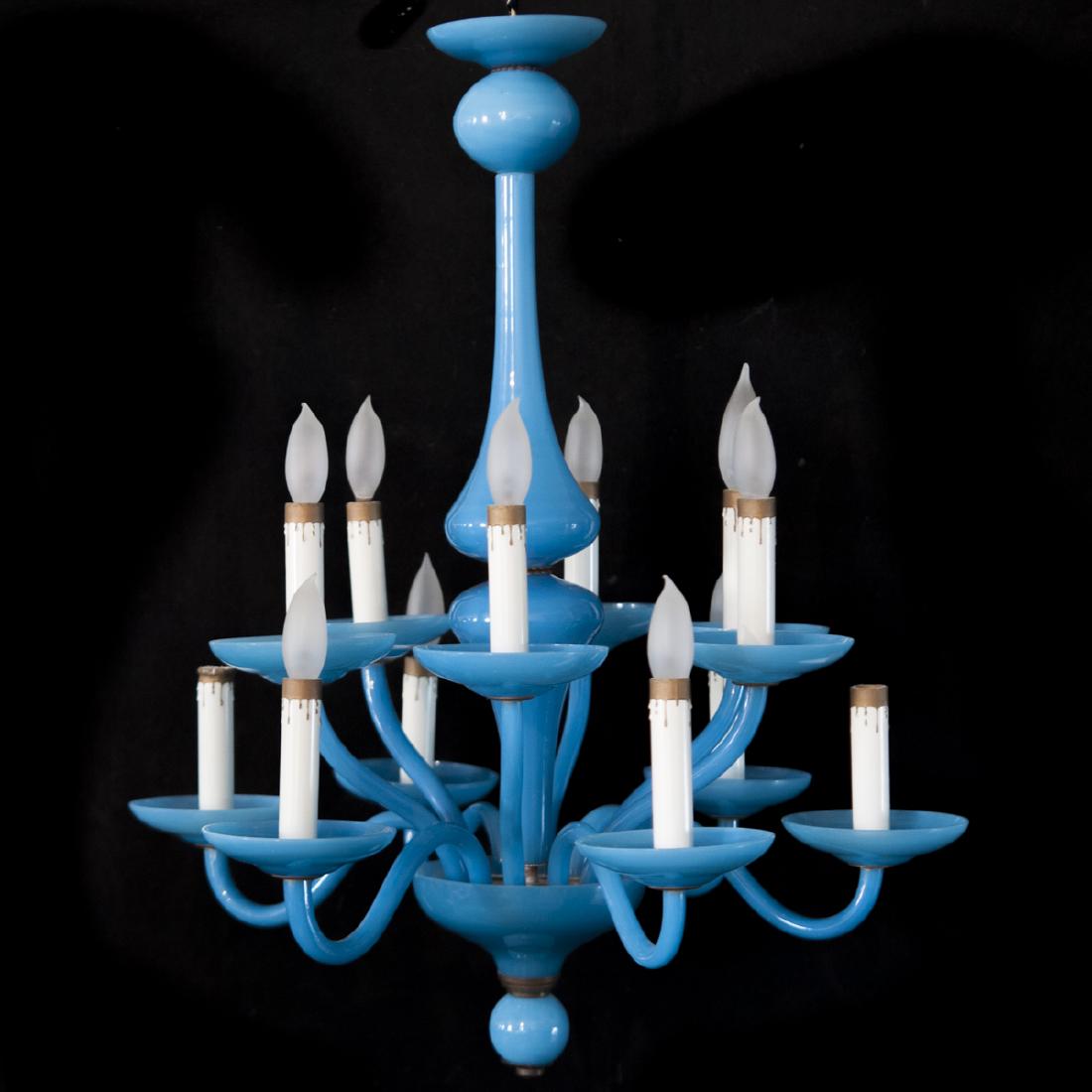 Opaline Glass Chandelier: DESCRIPTION: An opaline glass chandelier. Features a double fluted, conjoined stem, enveloped by 12 arms at alternating heights. Finished with candle motif bulb sockets and a rich blue opaline hue. CI