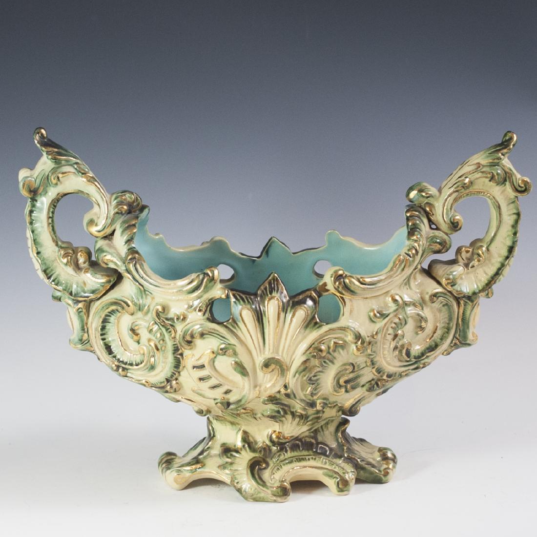 Wilhelm Schiller & Son Majolica Centerpiece: DESCRIPTION:Majolica ceramic centerpiece by Wilhelm Schiller & Son. Features ornate rococo style embossed designs along the body and arching side handles. Finished with gilded trim and olive green pol
