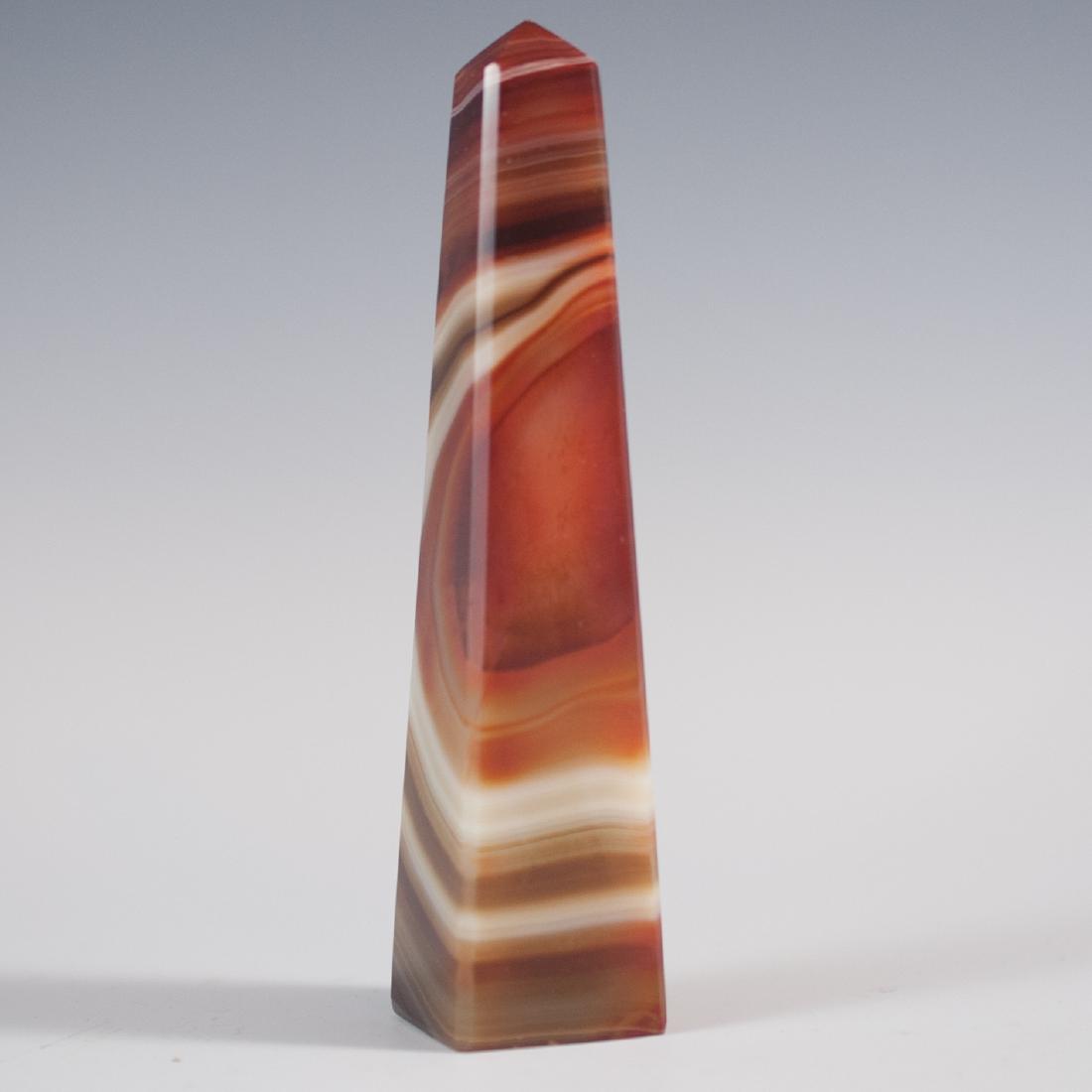Sardonyx Obelisk: DESCRIPTION: A polished sardonyx obelisk with beveled edges. The stone is cut to show flames of red outlined by rings of white and orange. CIRCA: 20th Ct. DIMENSIONS: 1'' W x 4 3/4'' H CONDITION: See