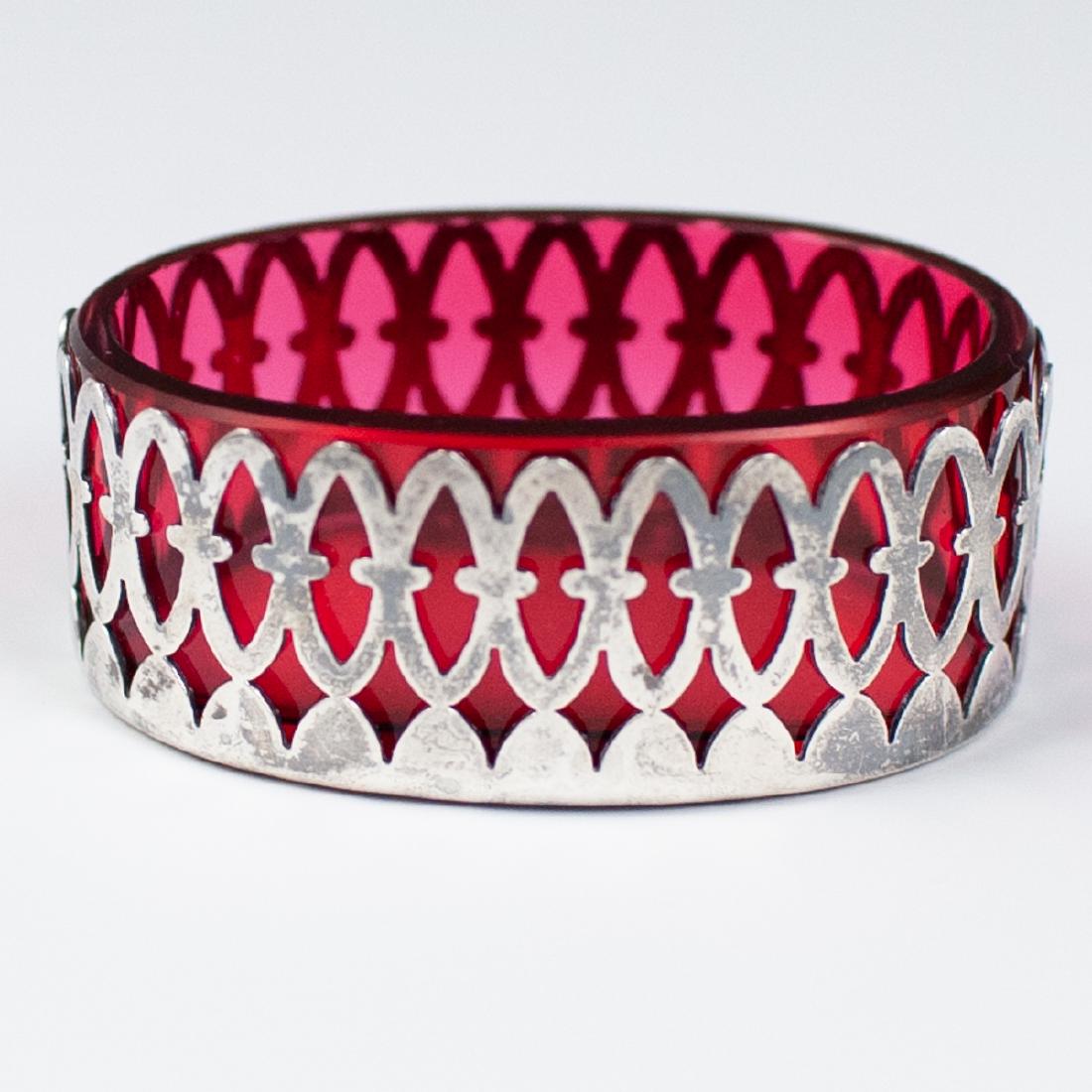 Sterling Salt Cellar: DESCRIPTION: A small sterling and cranberry glass salt cellar. Features an oval shape, with geometric motif body. Marked "Sterling" and ""81" on the bottom. CIRCA: 20th ORIGIN: DIMENSIONS: H:1" W:2.25
