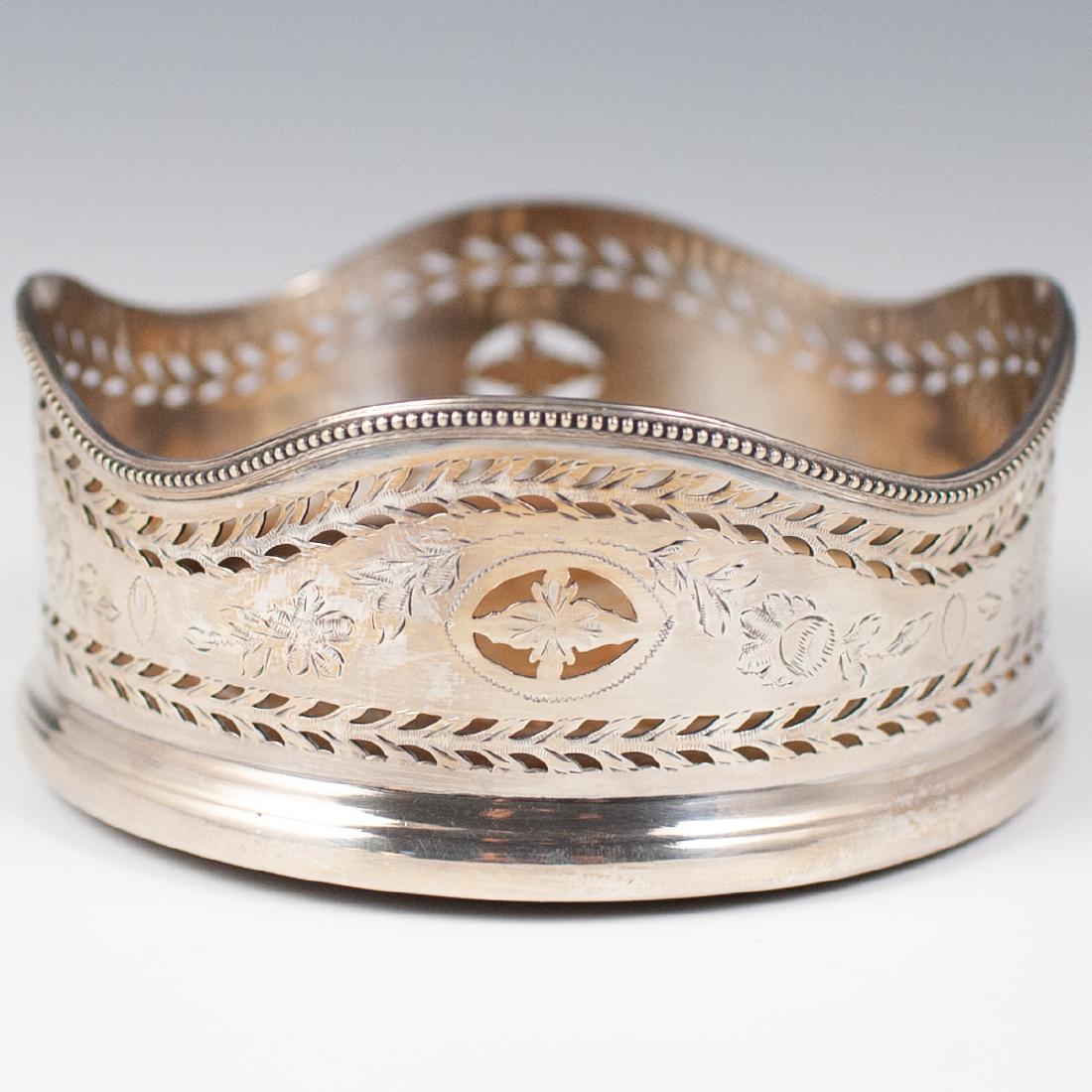 Vintage Silver Plated Wine Bottle Coaster: DESCRIPTION: A vintage silver plated wine bottle coaster. Features a sterling foundation, designed with a waved edged, embellished with open work leaf perforations, and engraved with further floral mo