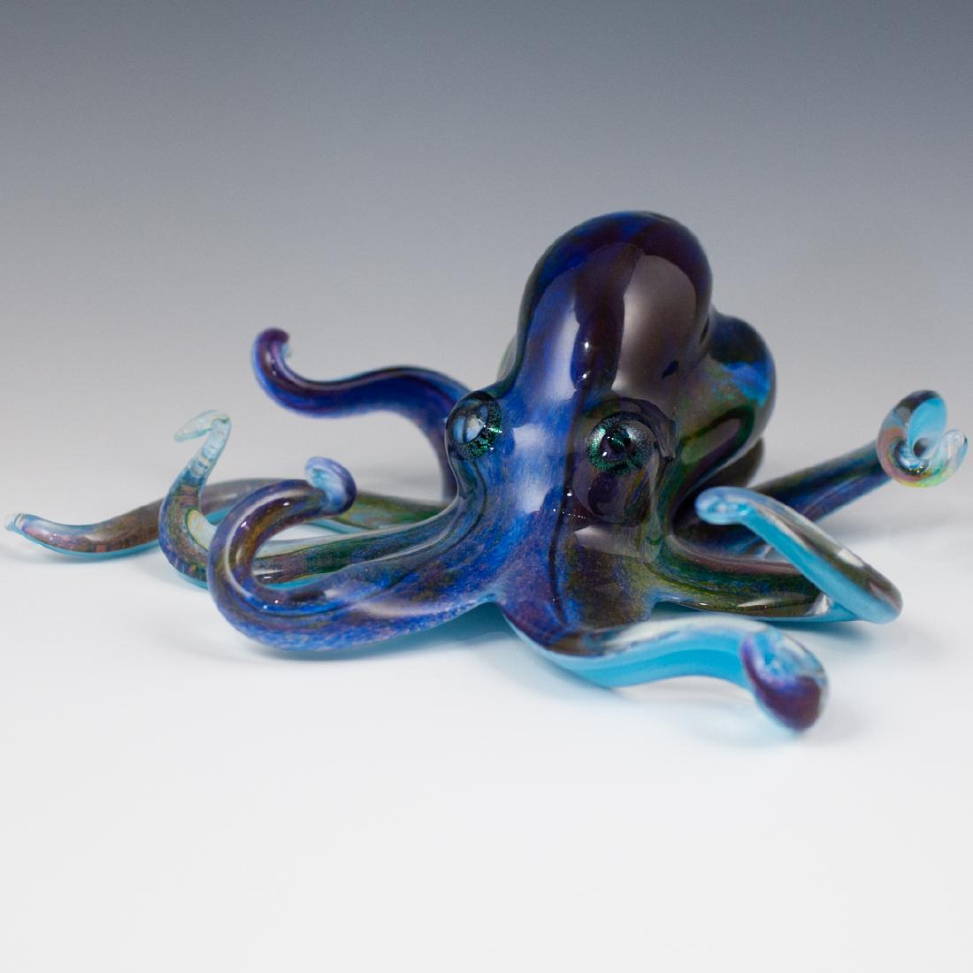 Michael Hopko Art Glass Octopus: DESCRIPTION: A hand blown art glass octopus by American artist Michael Hopko features an infusion of purple, blue, amber and green hues, finished with iridescent swirling eyes. Signed on the underside