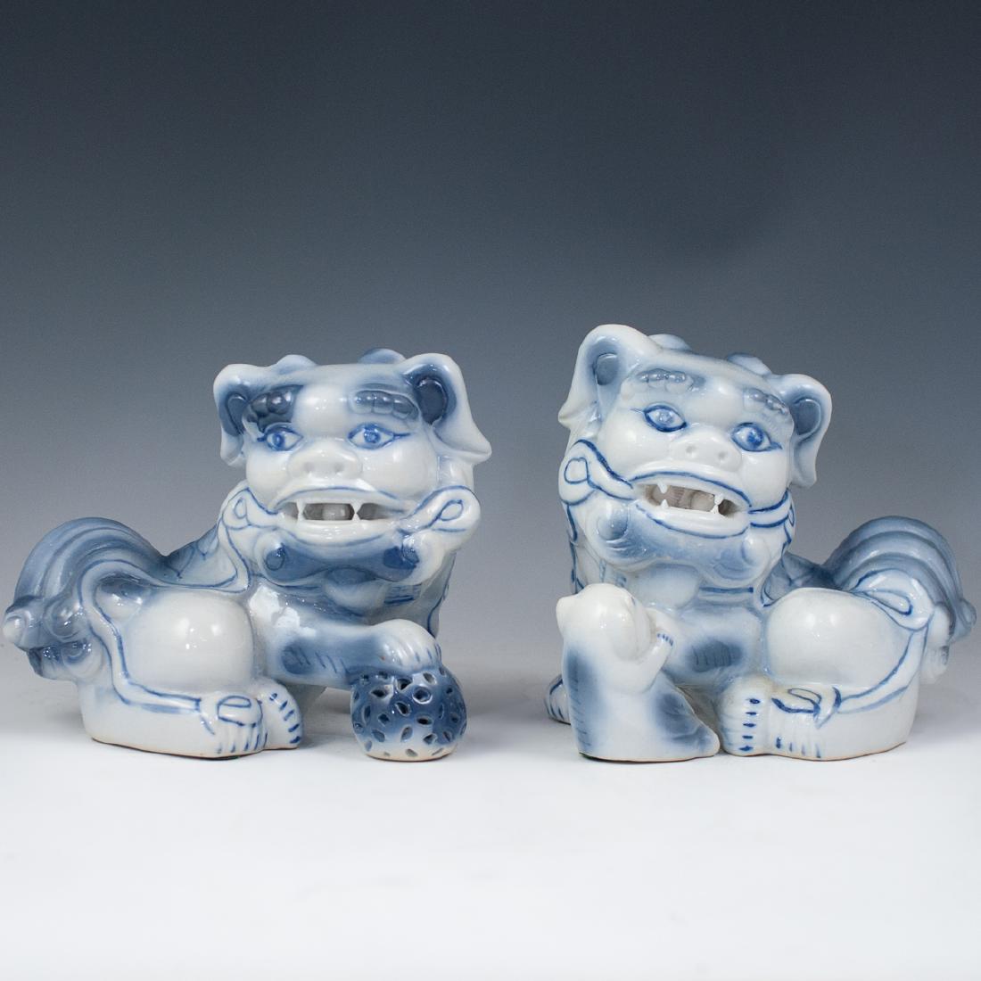 Pair Of Chinese Porcelain Foo Dogs: DESCRIPTION: A Chinese pair of porcelain foo dogs with a white base hue embellished with shades of blue, finished with a gloss glaze. CIRCA: Mid 20th Ct. ORIGIN: China DIMENSIONS: H: 6 1/4" L: 7 3/4" 