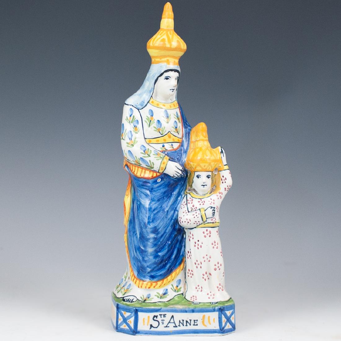 Quimper "Sainte Anne" Porcelain Figurine: DESCRIPTION: A porcelain figurine depicting Saint Anne with Marie child, handpainted with floral and spotted patterns on the dress, finished with a gloss glaze. Titled "Ste Anne" and marked on the und