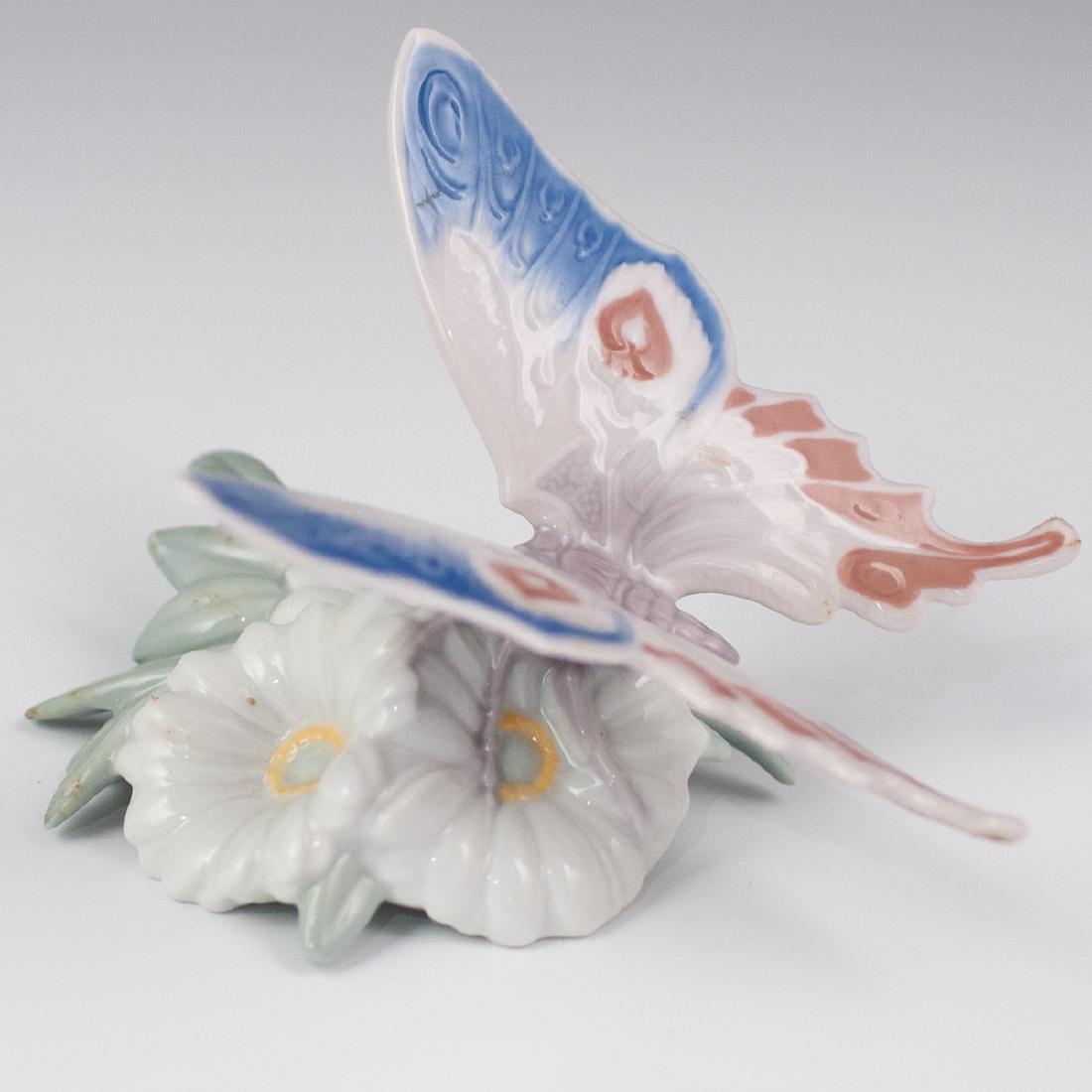 Lladro Daisy Butterfly Porcelain: DESCRIPTION: A Lladro porcelain figurine of a butterfly perched atop daisies in a realistic rendition. Marked along the underside with Lladro backstamps. CIRCA: Late 20th-21st Ct. ORIGIN: Spain DIMENS