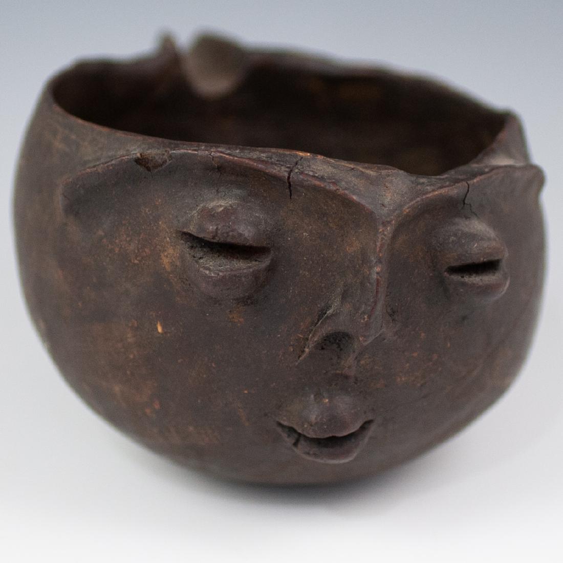 Pre-Columbian Wooden Pouring Vessel: DESCRIPTION: A wooden pre-columbian pouring vessel features facial relief carvings with a pouring spout. ORIGIN: Central America DIMENSIONS: H: 4 1/2" L: 10 1/4: W: 6 5/8" CONDITION: Great condition. 
