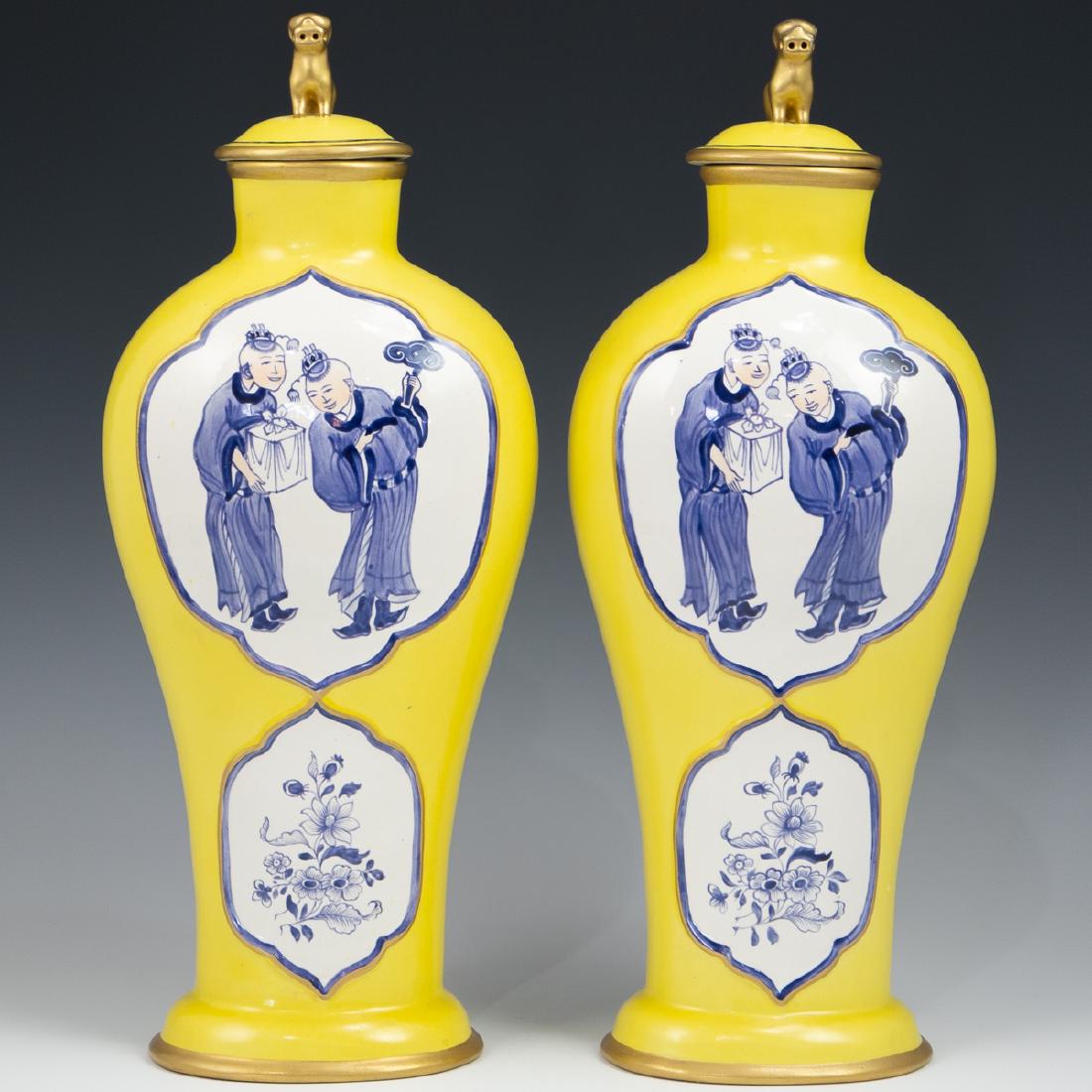 Pair Of Porcelain Mottahedeh Urns: DESCRIPTION: Pair of porcelain Mottahedeh urns feature in a yellow ground hue, decorated on both sides with blue and white chinese celebration scenes with floral patterns. Finished with gilded trim an