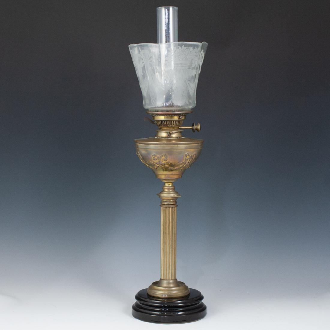 Messenger Gilded Brass Oil Lamp: DESCRIPTION: Messenger oil lamp composed of a brass foundation featuring a corinthian column body leading up to the oil tank garnished with tied ribbon motifs. Sitting at the top is a clear glass lamp