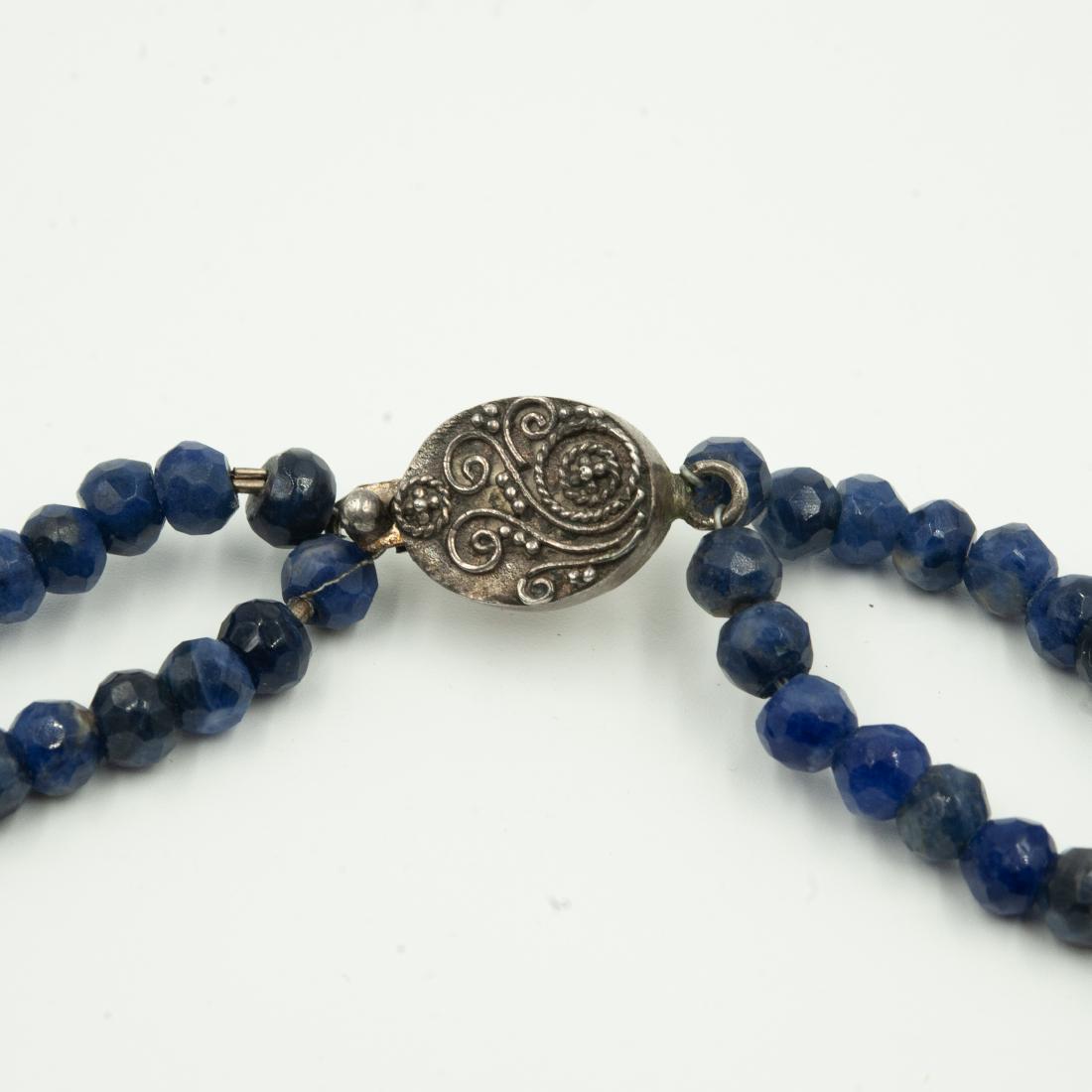 Faceted Lapis & Sterling Choker Necklace: DESCRIPTION: A necklace composed of two strands of beaded, faceted lapis lazuli beads convening at a sterling clasp with filigree floral motifs. The beads are intersected by channel set synthetic sapp