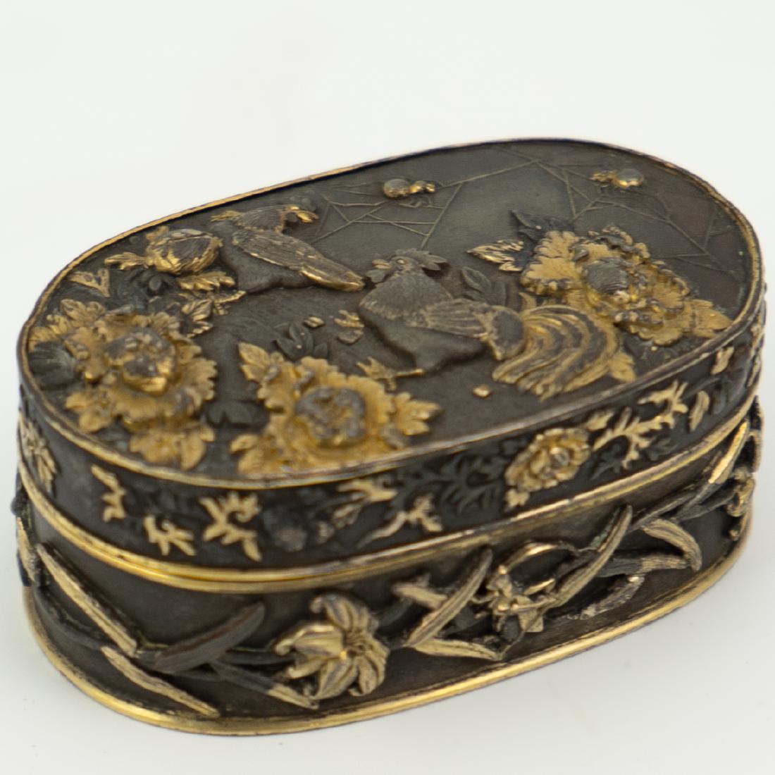 Japanese Meiji Period Bronze and Gold Box: DESCRIPTION: Japanese Meiji Period Bronze and Gold Box. Features an oval form depicting roosters, spiders and flowers. CIRCA: 19th Ct. ORIGIN: Japan DIMENSIONS: L:2.5" W:1.5" H:1" CONDITION: Great con