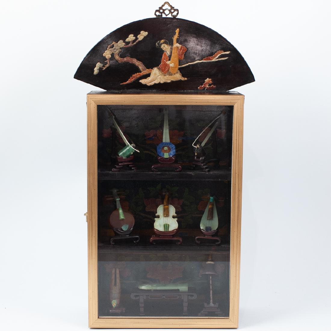 (9 pc) Collection of Chinese Carved Jade Miniature: DESCRIPTION: A Group of 9 Chinese carved jade miniature musical instruments on carved hardwood stands. Encased within a rosewood display box, finished with an inlaid hardstone female musician on the t