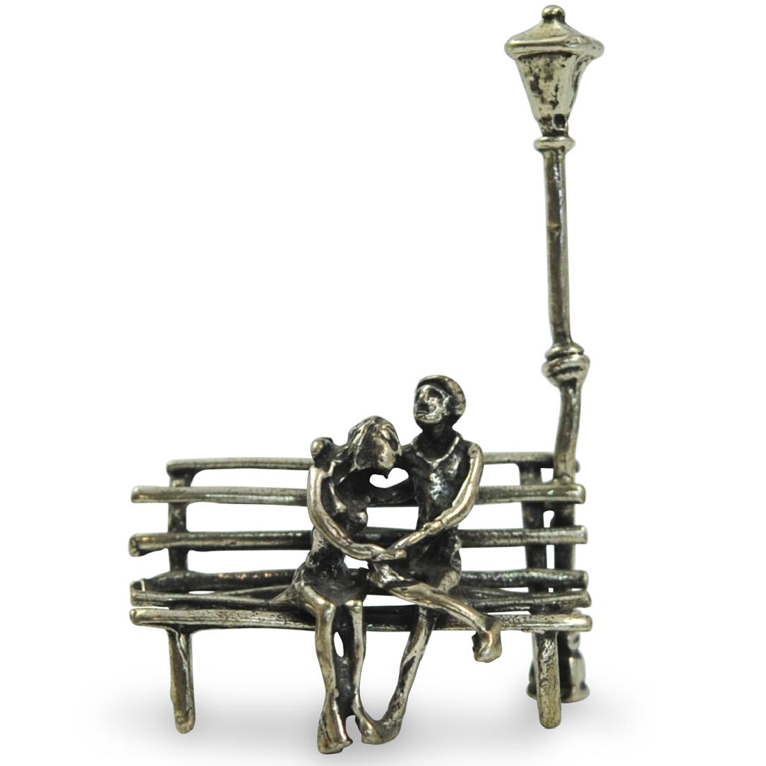 Sterling Silver Figurine: DESCRIPTION: A sterling silver figurine. Features a seated couple embracing each other under a street light, marked along the back "800" CIRCA: 20th Cent. ORIGIN: USA DIMENSIONS: H: 2.5" W: 1.5" CONDI