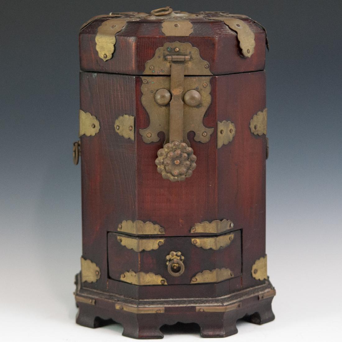 Japanese Wood & Brass Box: DESCRIPTION: A Japanese wooden box featuring a beveled, octagonal design, embellished with brass hardware along the body. The interior is lined with paper with an array of Japanese characters. Finishe
