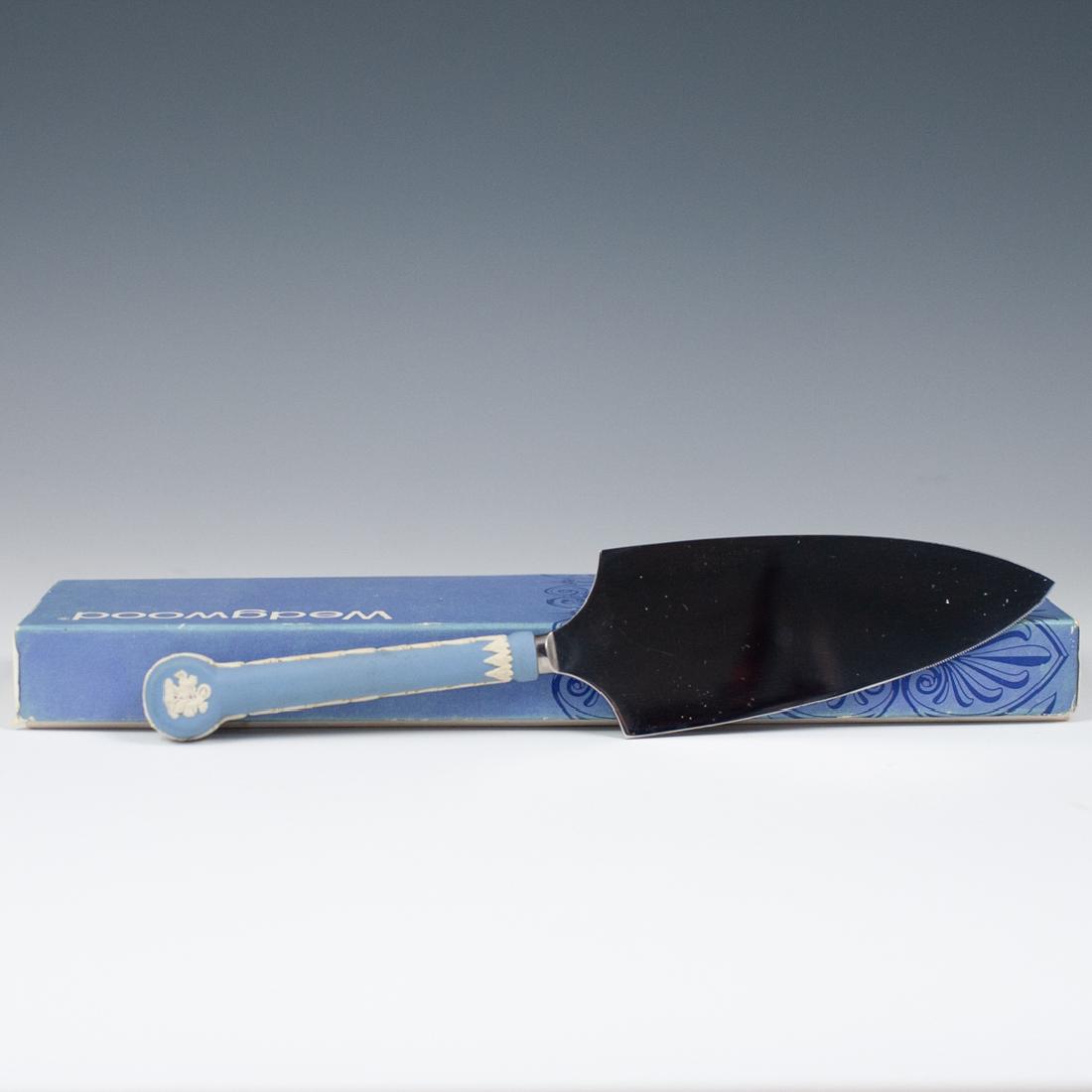 Wedgwood Jasperware Cake Knife: DESCRIPTION: A wedgewood blue Jasperware cake knife features a porcelain handle embellished with Roman chariot and floral banner decorations, Marked "Wedgwood England" and Fitted with a stainless stee